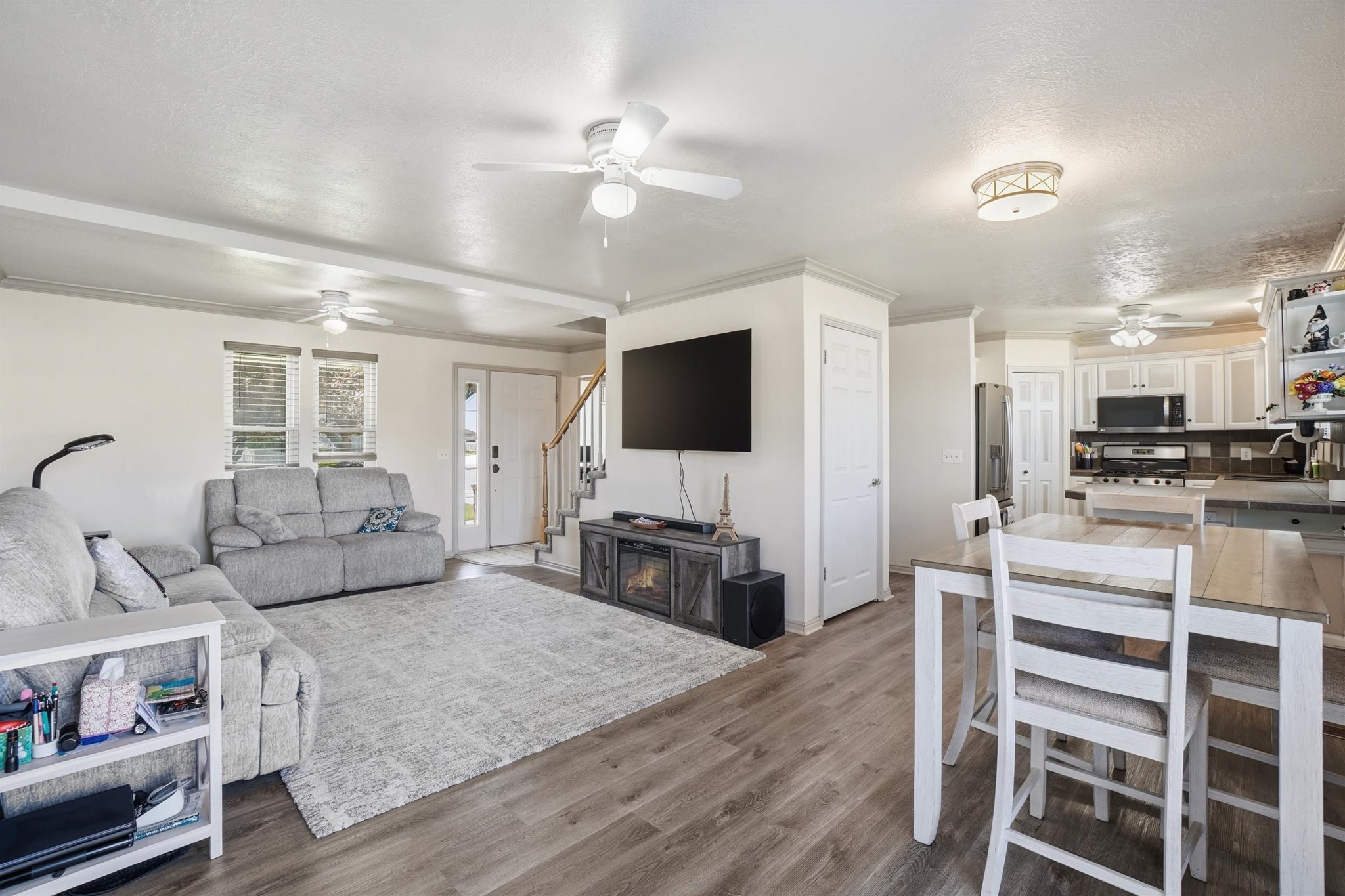 Open-concept living space featuring wood-finish flooring, white walls, and crown molding
