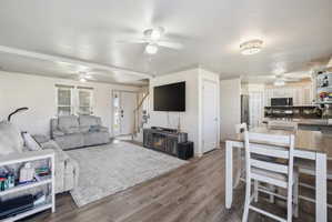 Open-concept living space featuring wood-finish flooring, white walls, and crown molding