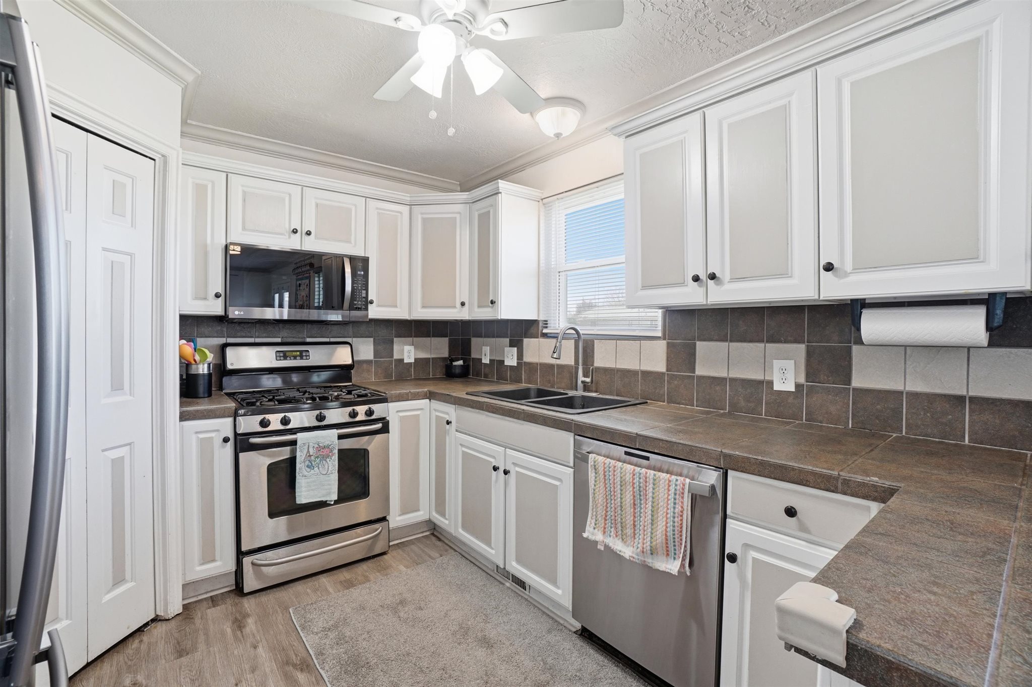 Kitchen featuring white cabinetry, stainless steel appliances, a double basin sink, and wood-finish flooring