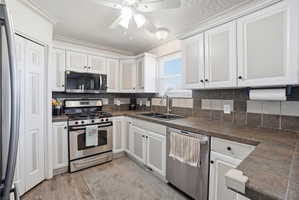 Kitchen featuring white cabinetry, stainless steel appliances, a double basin sink, and wood-finish flooring