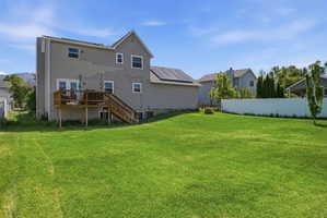 Spacious rear lawn with a full wooden deck and stairs