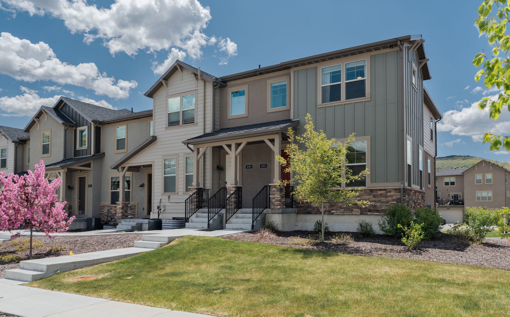 Craftsman inspired home with stone siding, a front yard, board and batten siding, and a residential view