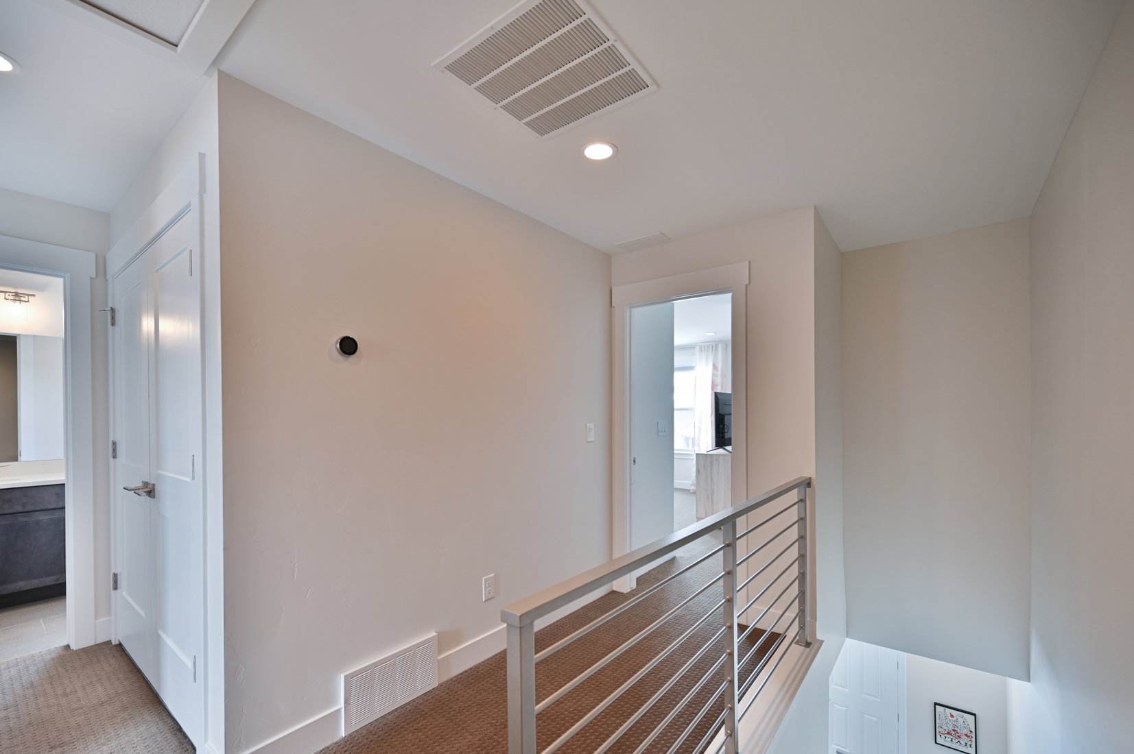 Hall with an upstairs landing, light colored carpet, and recessed lighting