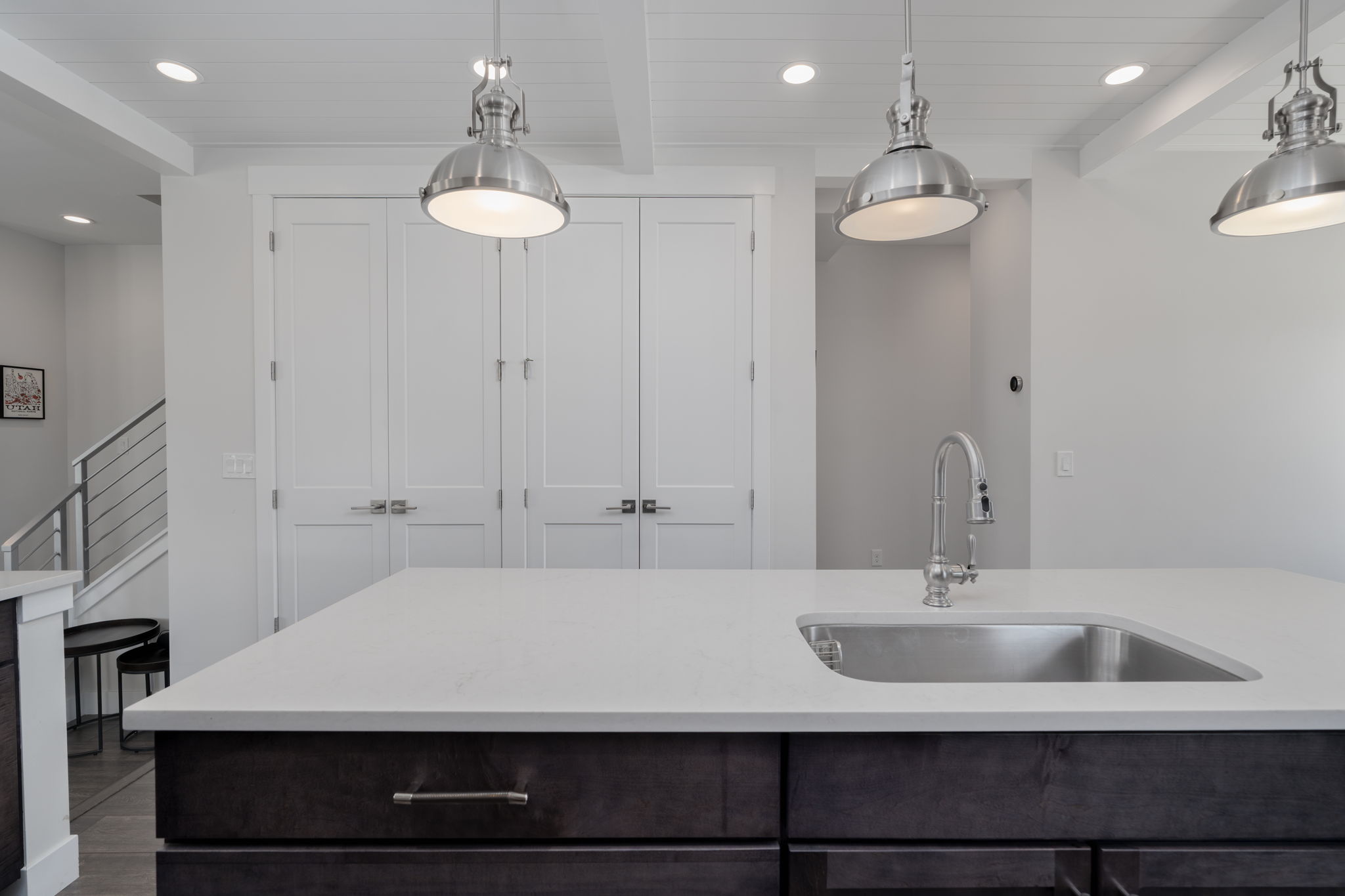 Kitchen with beamed ceiling, dark wood finish cabinetry, pendant lighting, light stone countertops, and dark wood-style flooring