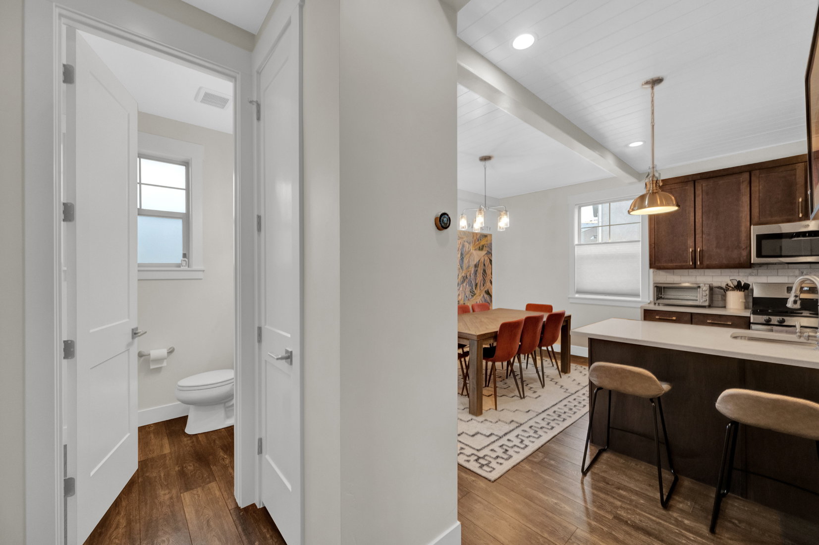 Kitchen with dark wood finished floors, dark wood finish cabinetry, a breakfast bar area, tasteful backsplash, and decorative light fixtures