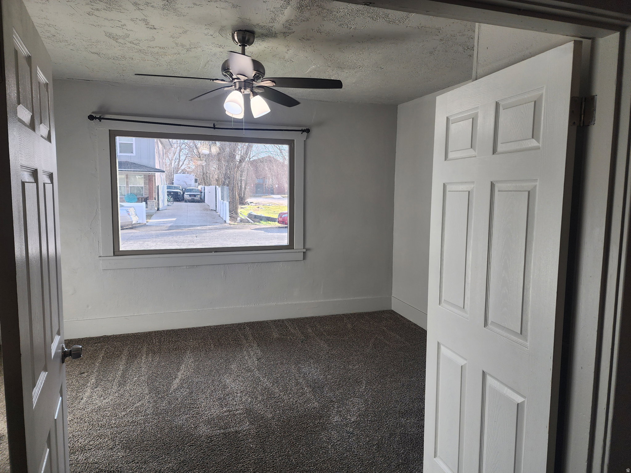 Spare room with dark carpet and a ceiling fan