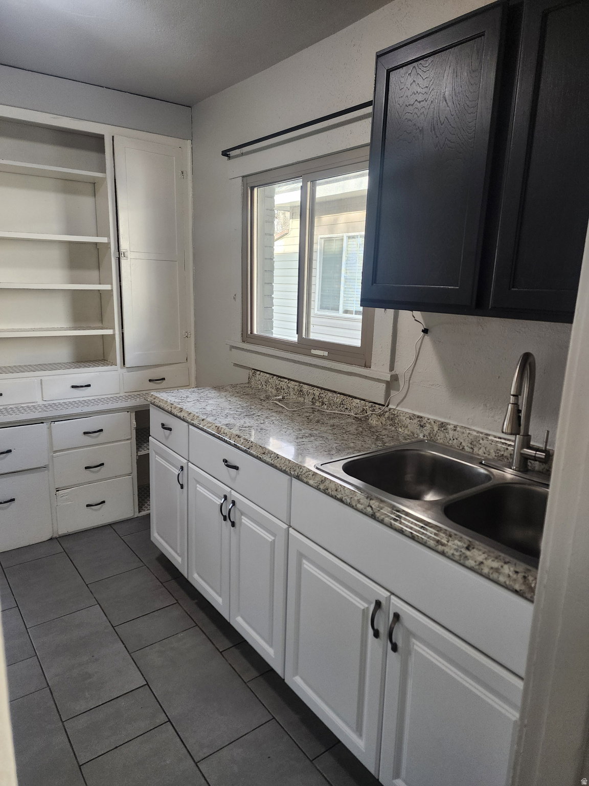 Kitchen with white cabinetry and dark tile patterned floors
