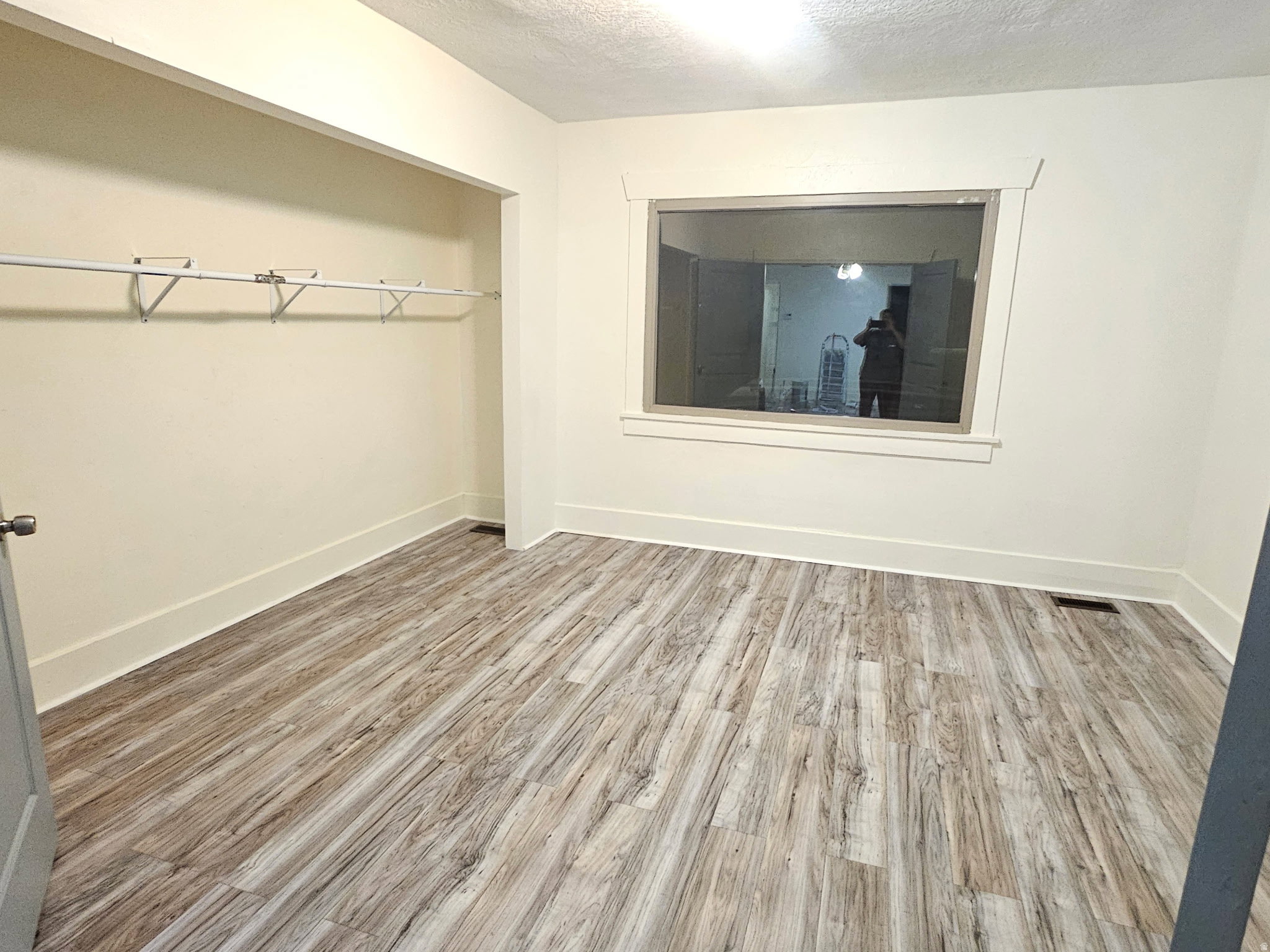 Unfurnished bedroom with light wood-type flooring, a textured ceiling, and a closet