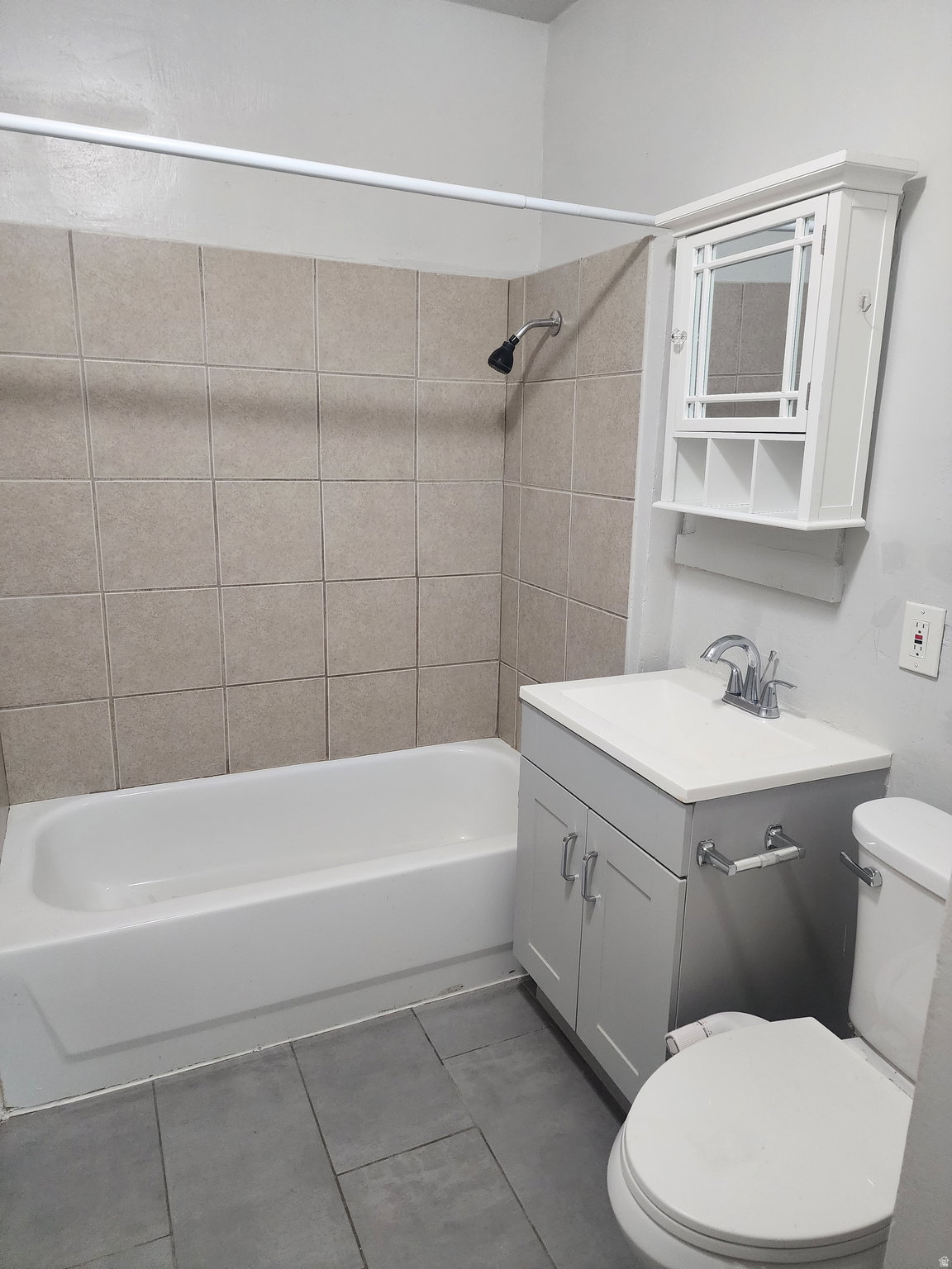 Full bath featuring vanity, shower / bathtub combination, and dark tile patterned floors