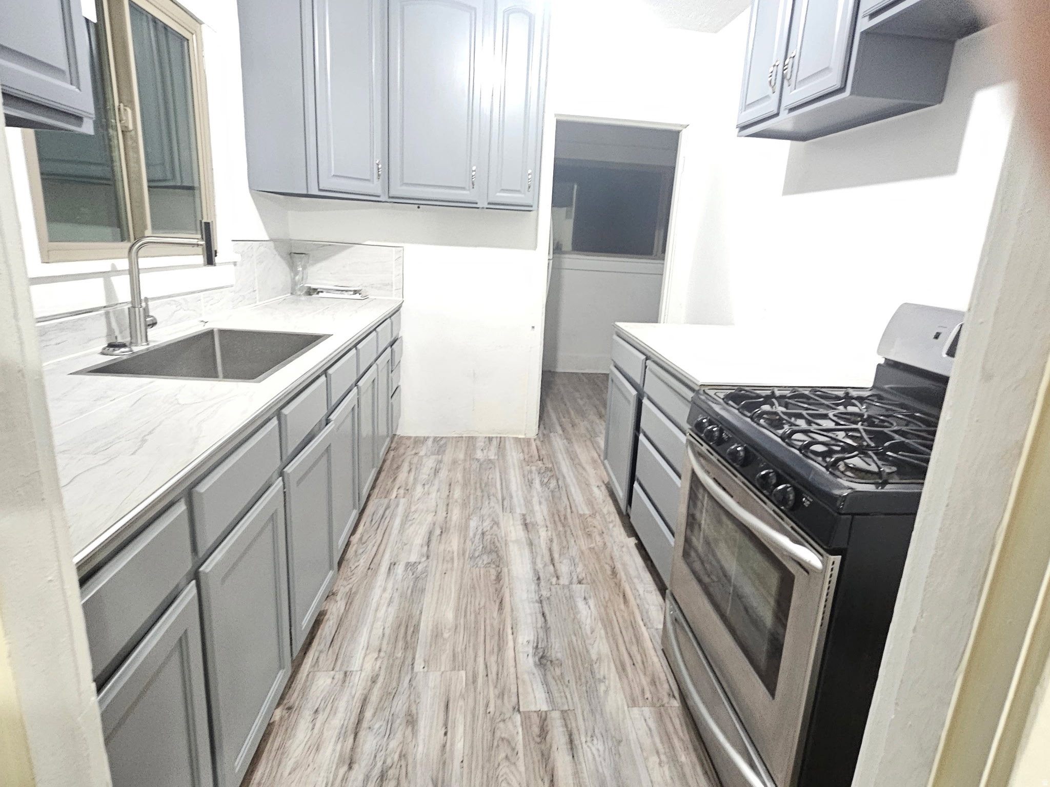 Kitchen with gas range, gray cabinets, and light wood-style floors