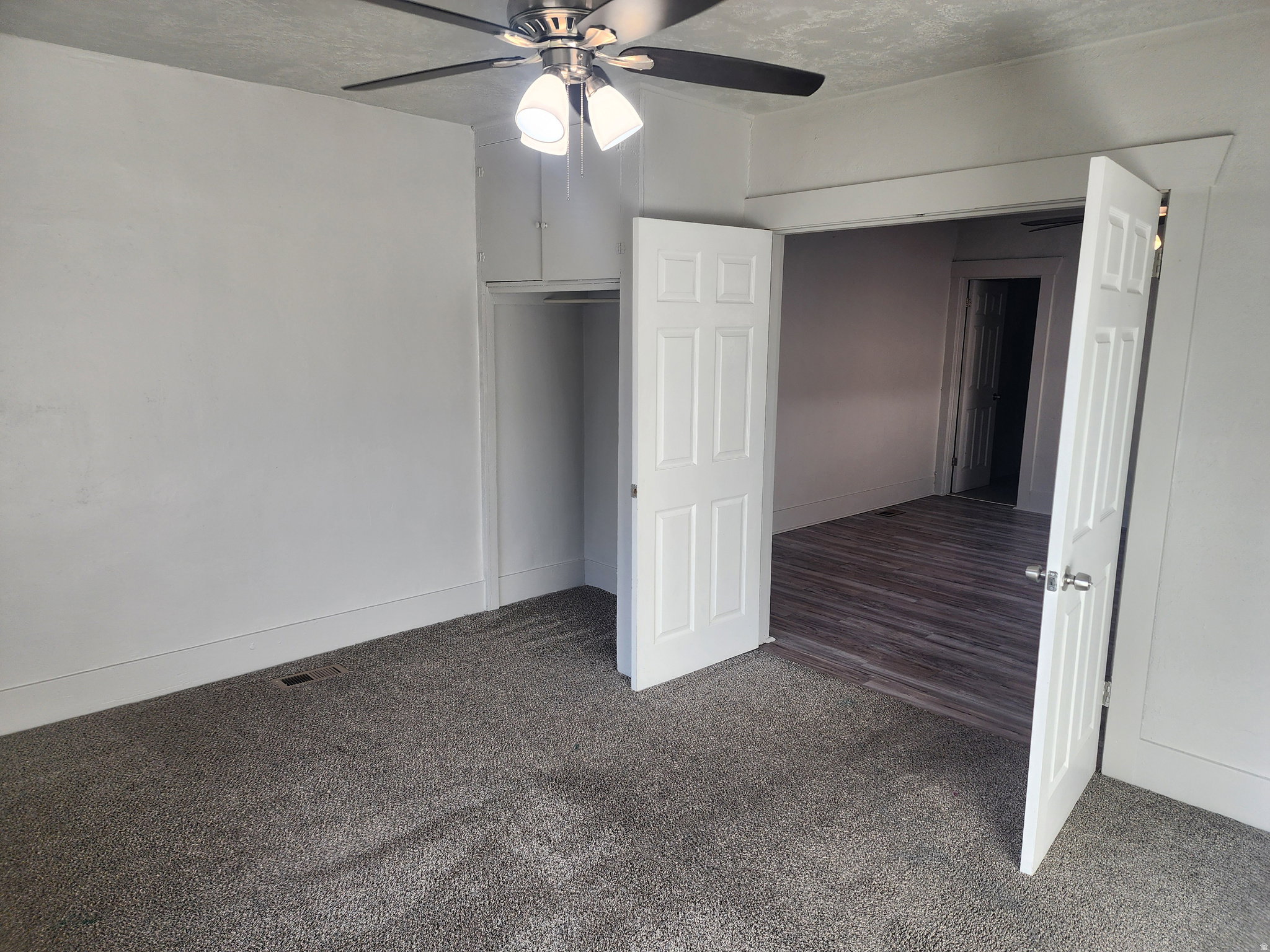 Unfurnished bedroom with dark colored carpet, a textured ceiling, a ceiling fan, and a closet