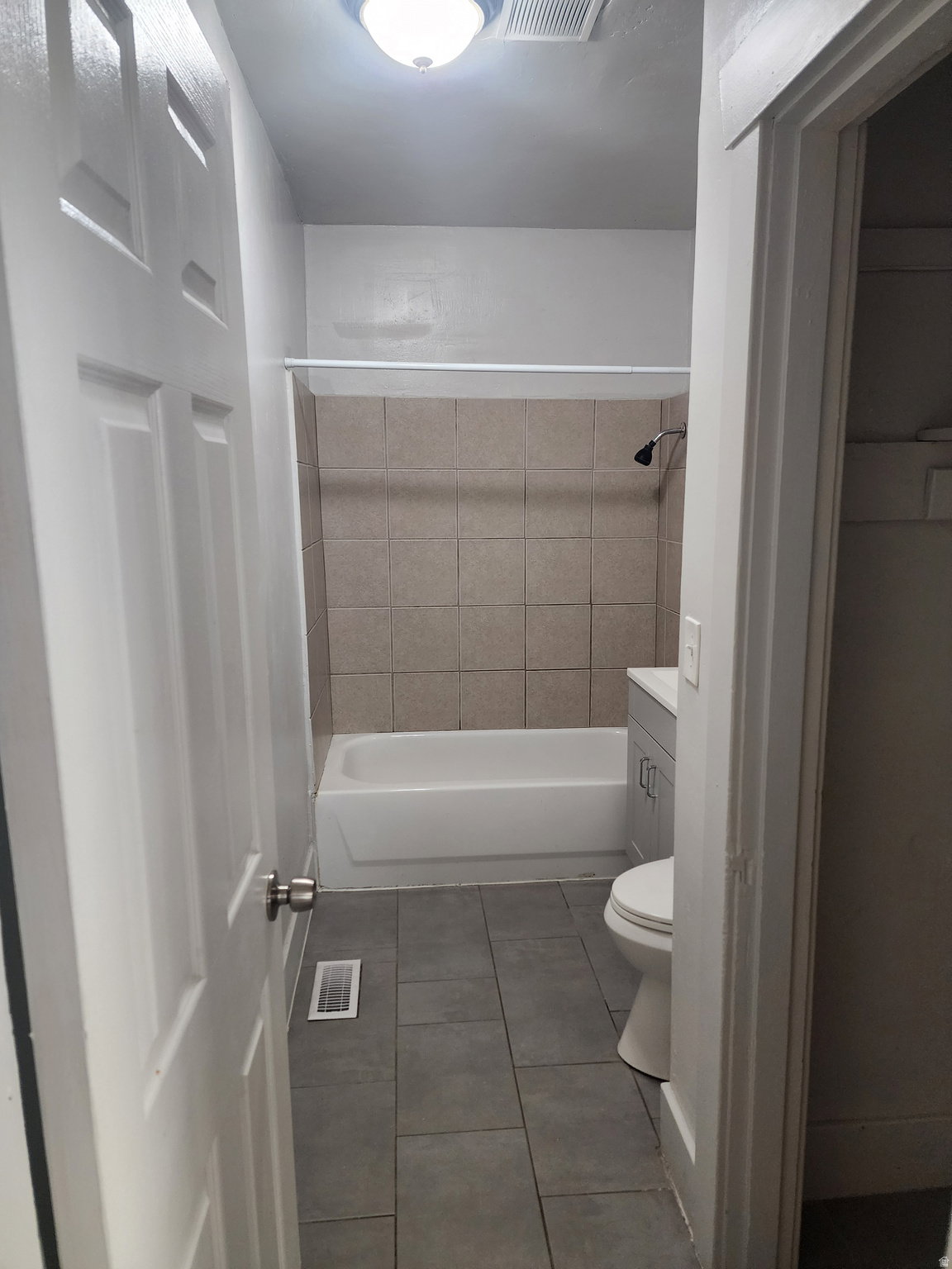 Bathroom with dark tile patterned flooring, vanity, and shower / washtub combination