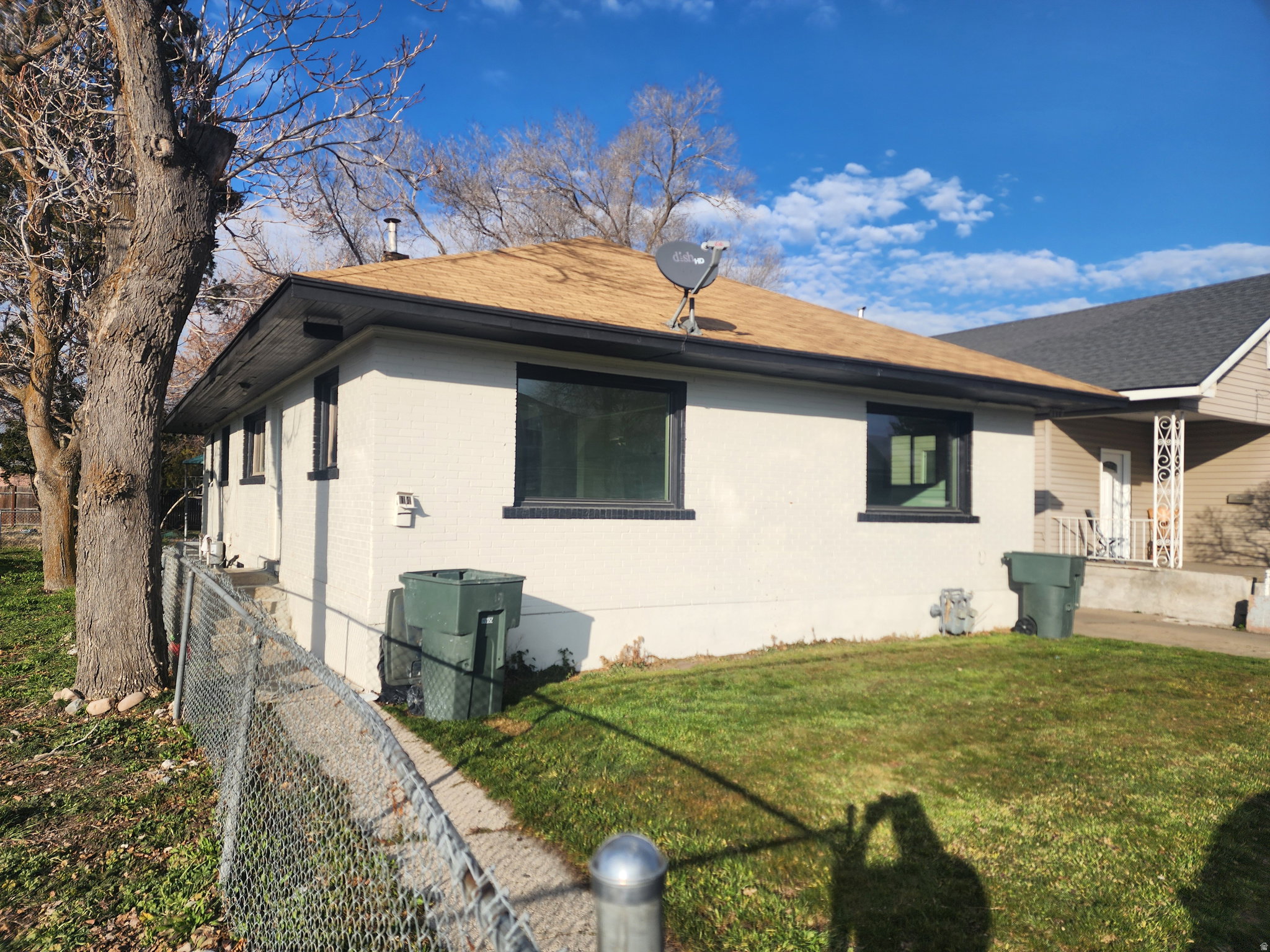 View of home's exterior featuring brick siding, roof with shingles, and covered porch