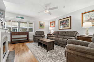 Living area with ceiling fan, light wood-style flooring, and a baseboard heating unit