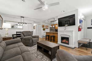 Living room with light wood finished floors, a glass covered fireplace, a ceiling fan, and recessed lighting