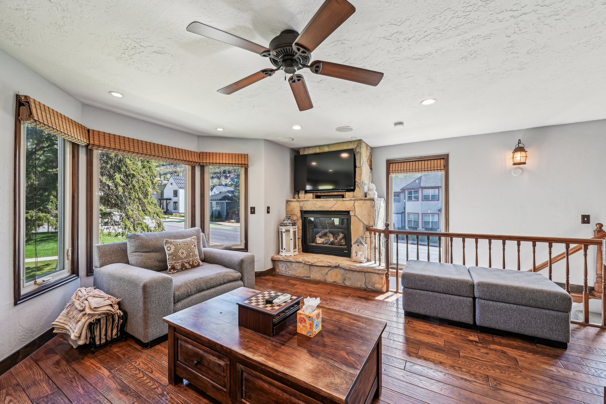 Living area featuring dark wood-style floors, a stone fireplace, a ceiling fan, a textured ceiling, and recessed lighting