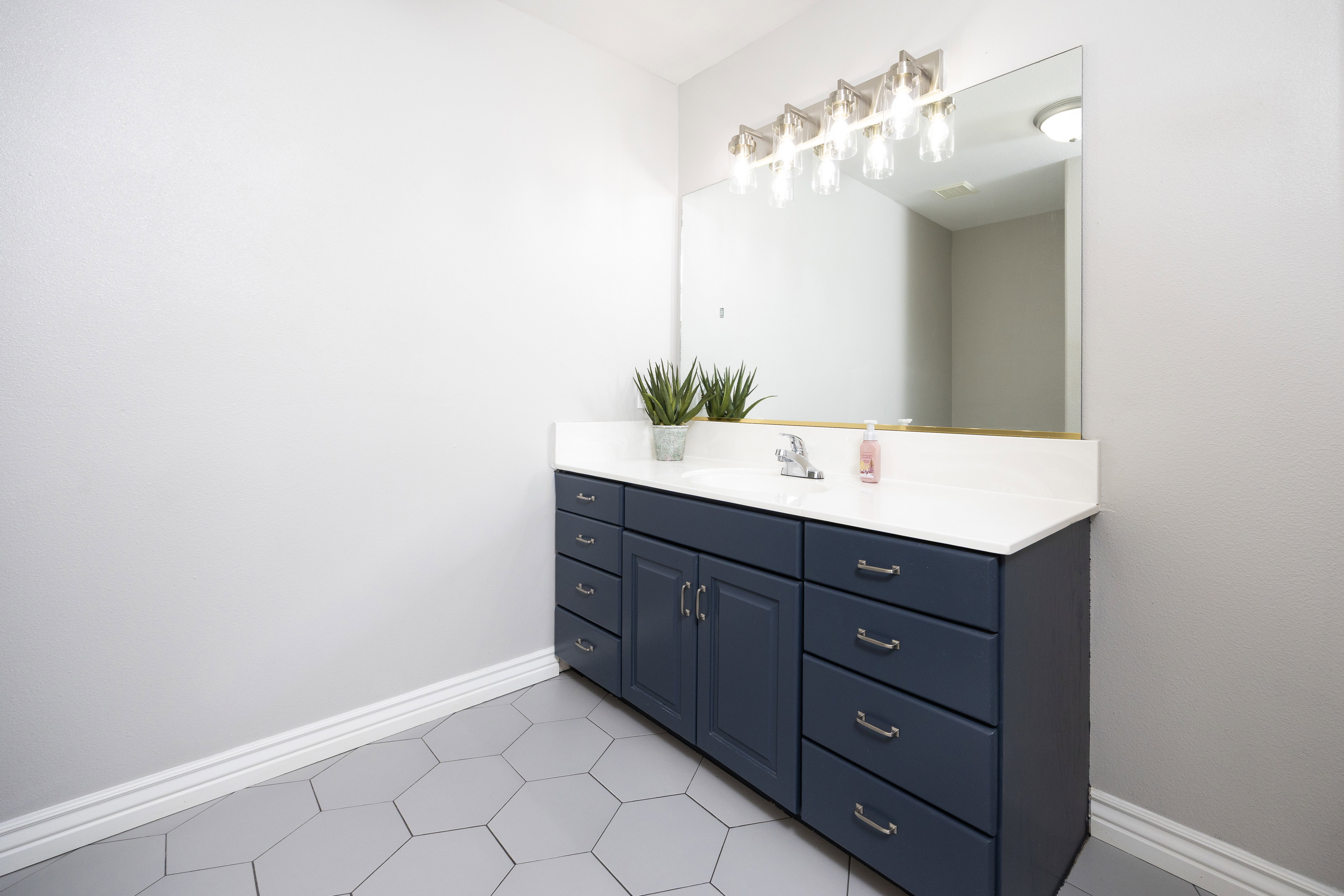Bathroom featuring a wide vanity with a white countertop, an undermount sink, and a chrome faucet