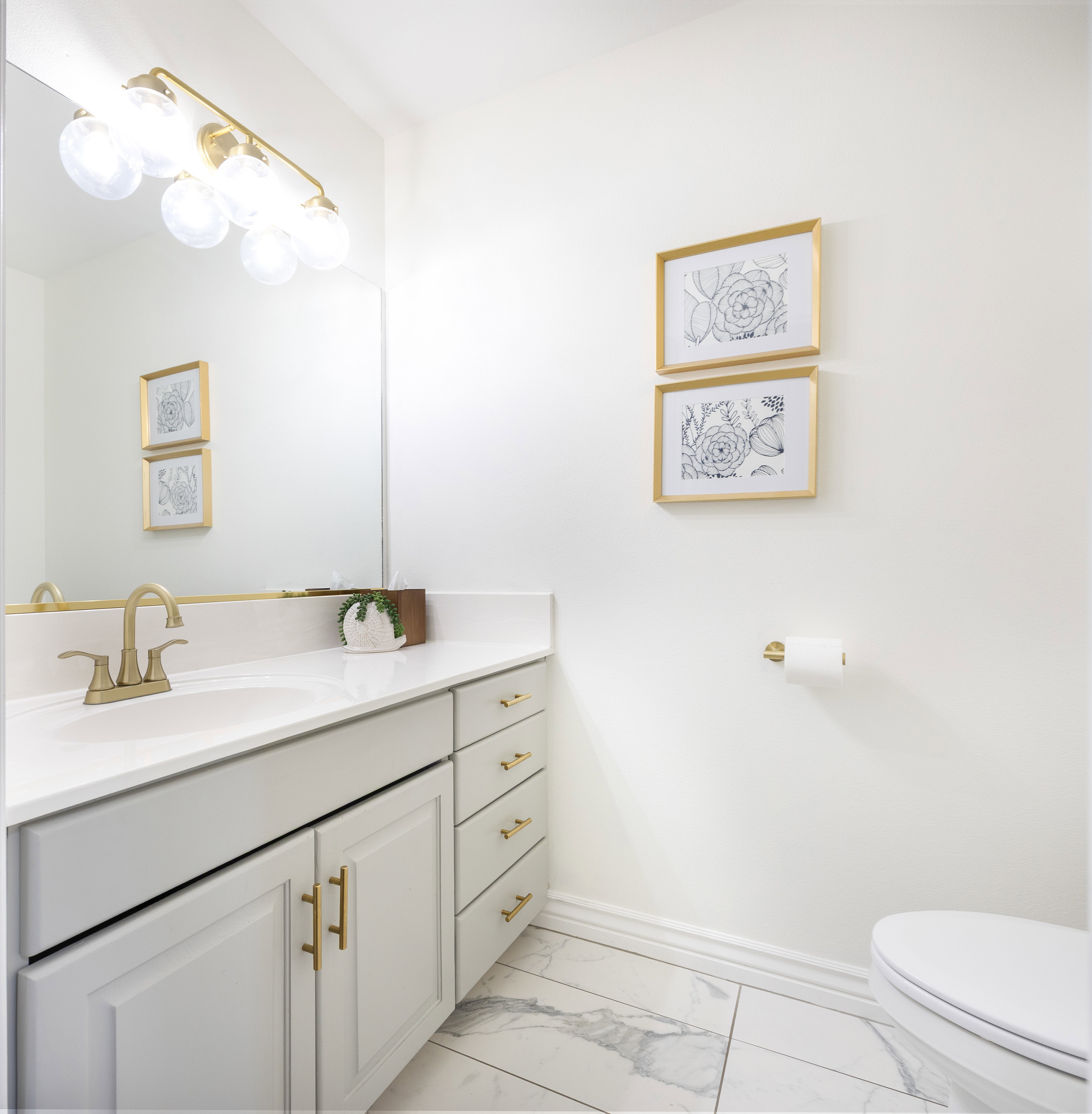 Bathroom featuring a vanity with white cabinetry, gold-tone hardware, and a white countertop