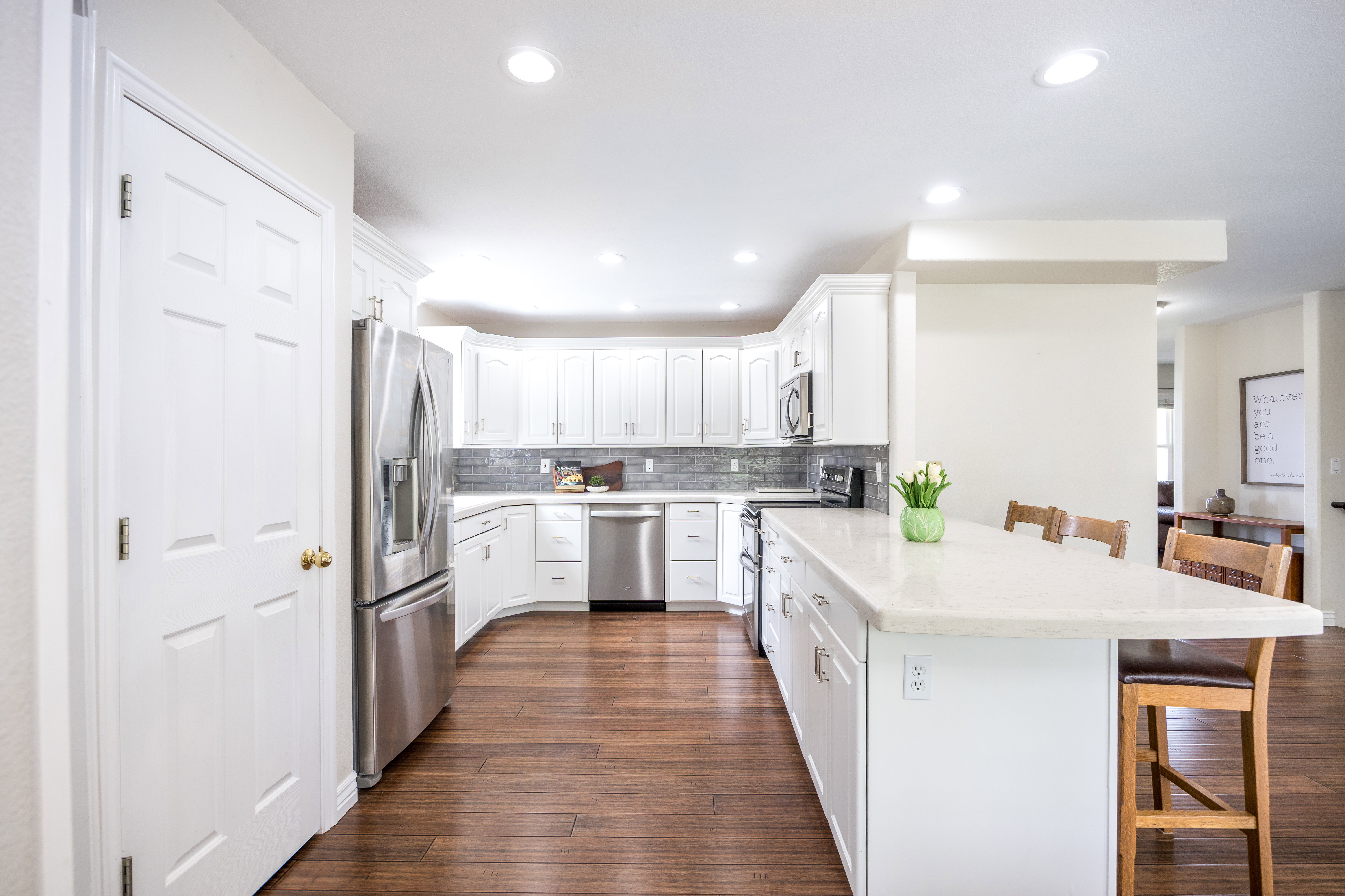 Modern kitchen featuring white cabinetry, stainless steel appliances, a tile backsplash, and wood-finish flooring