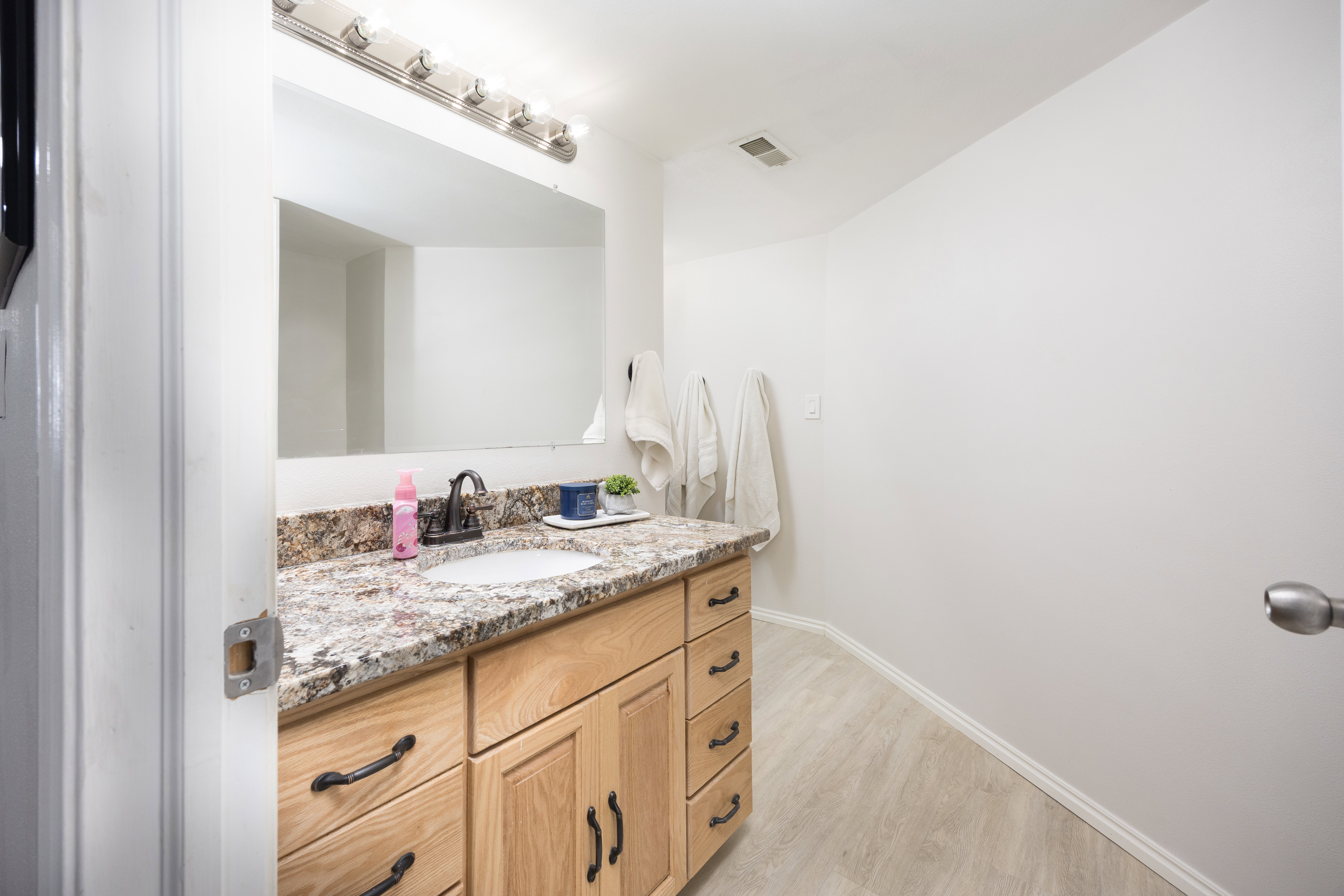Bathroom featuring a wood-finish vanity with an undermount sink, granite countertop, and oil-rubbed bronze faucet