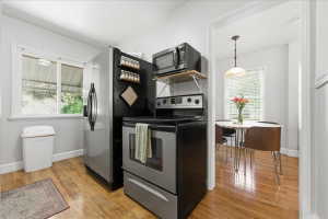 Kitchen featuring stainless steel appliances, light wood-style floors, and pendant lighting