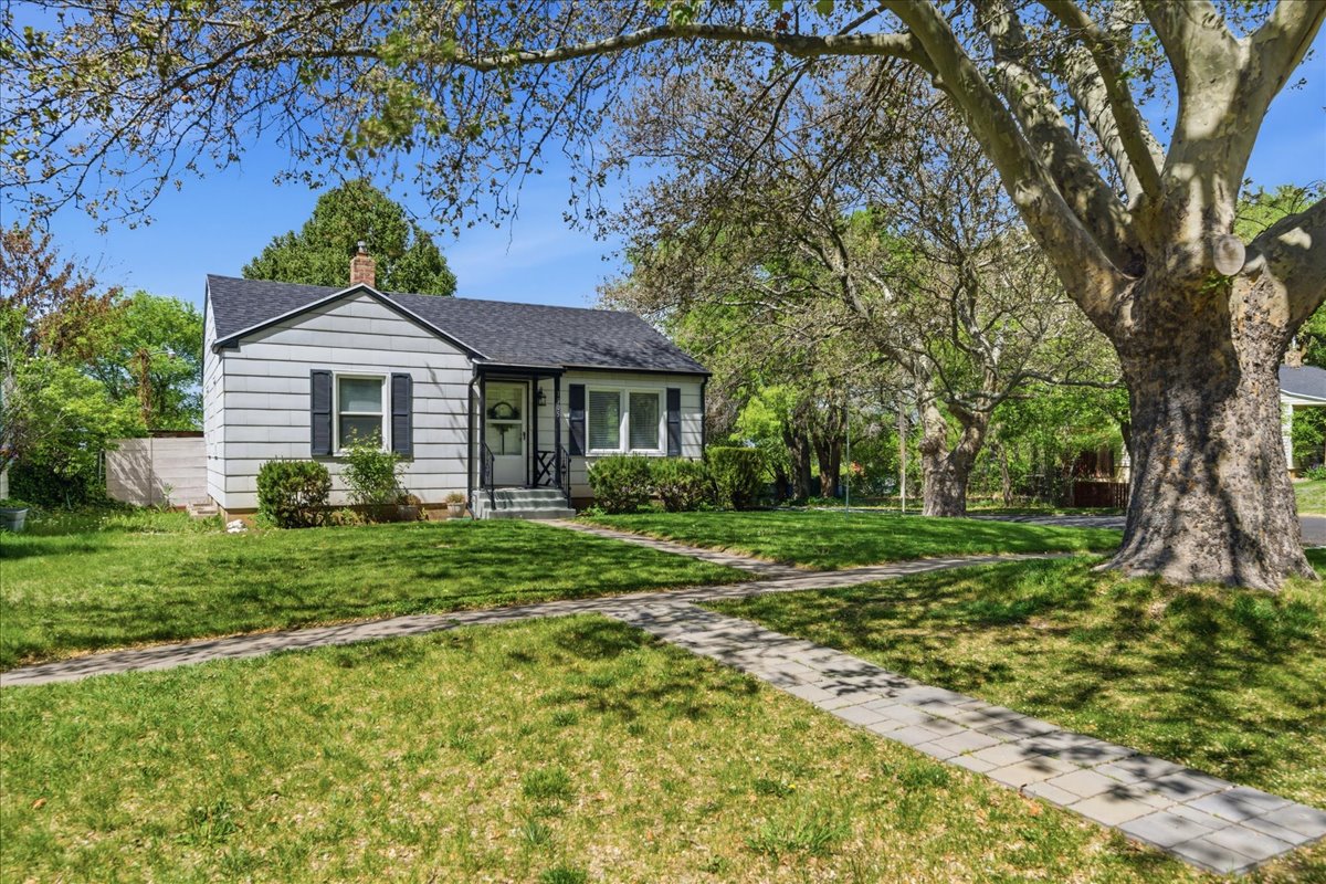 View of front of property with a chimney, roof with shingles, and a front yard