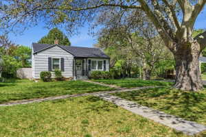 View of front of property with a chimney, roof with shingles, and a front yard