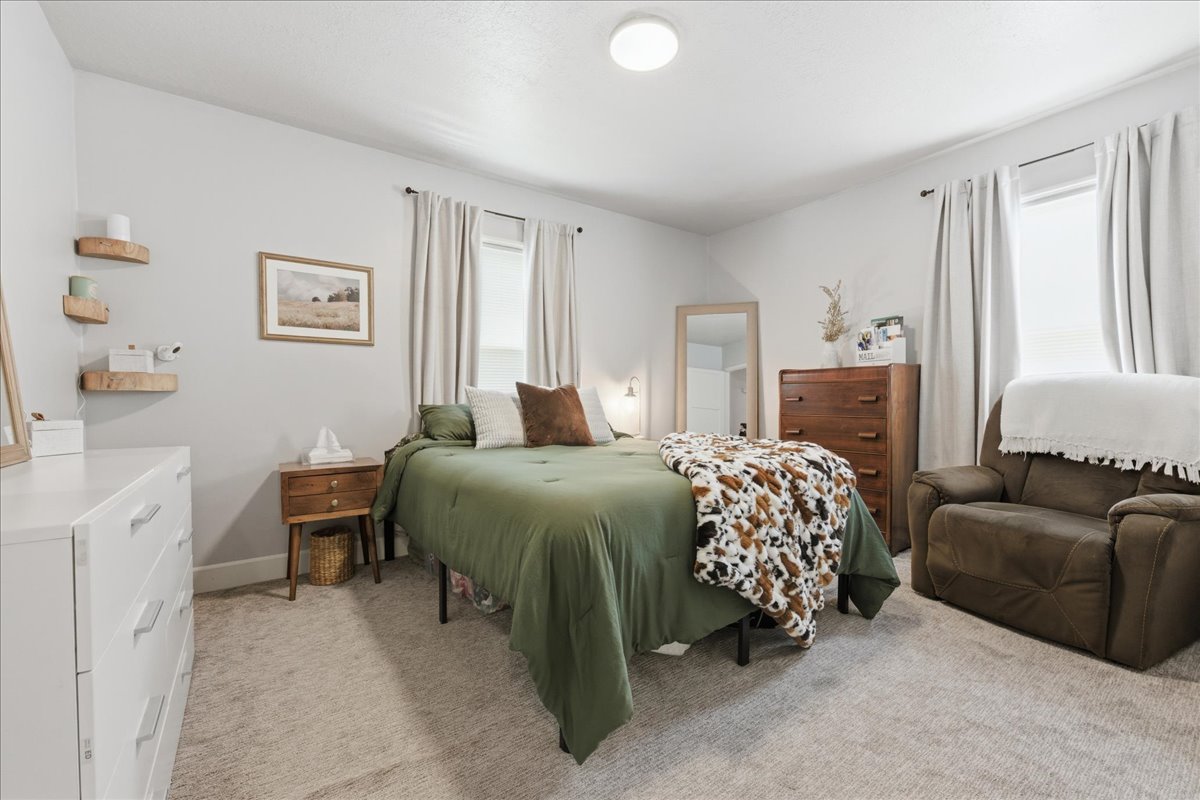 Bedroom featuring light colored carpet and multiple windows