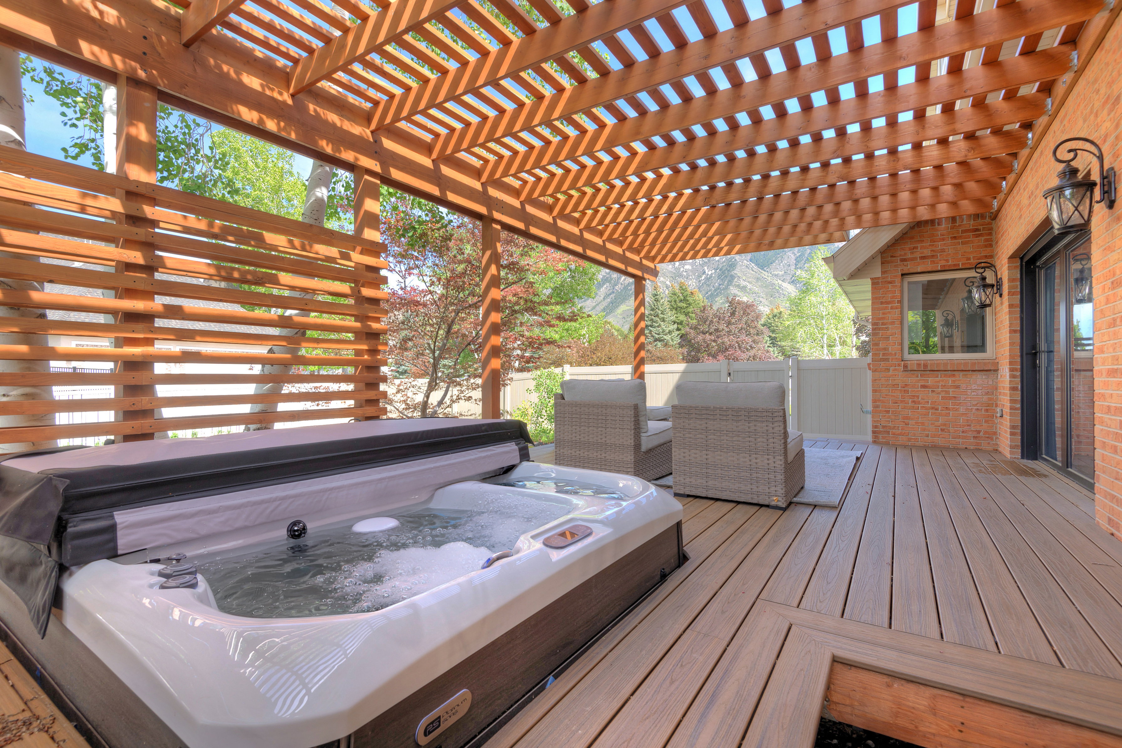 Wooden terrace with a covered hot tub and a mountain view