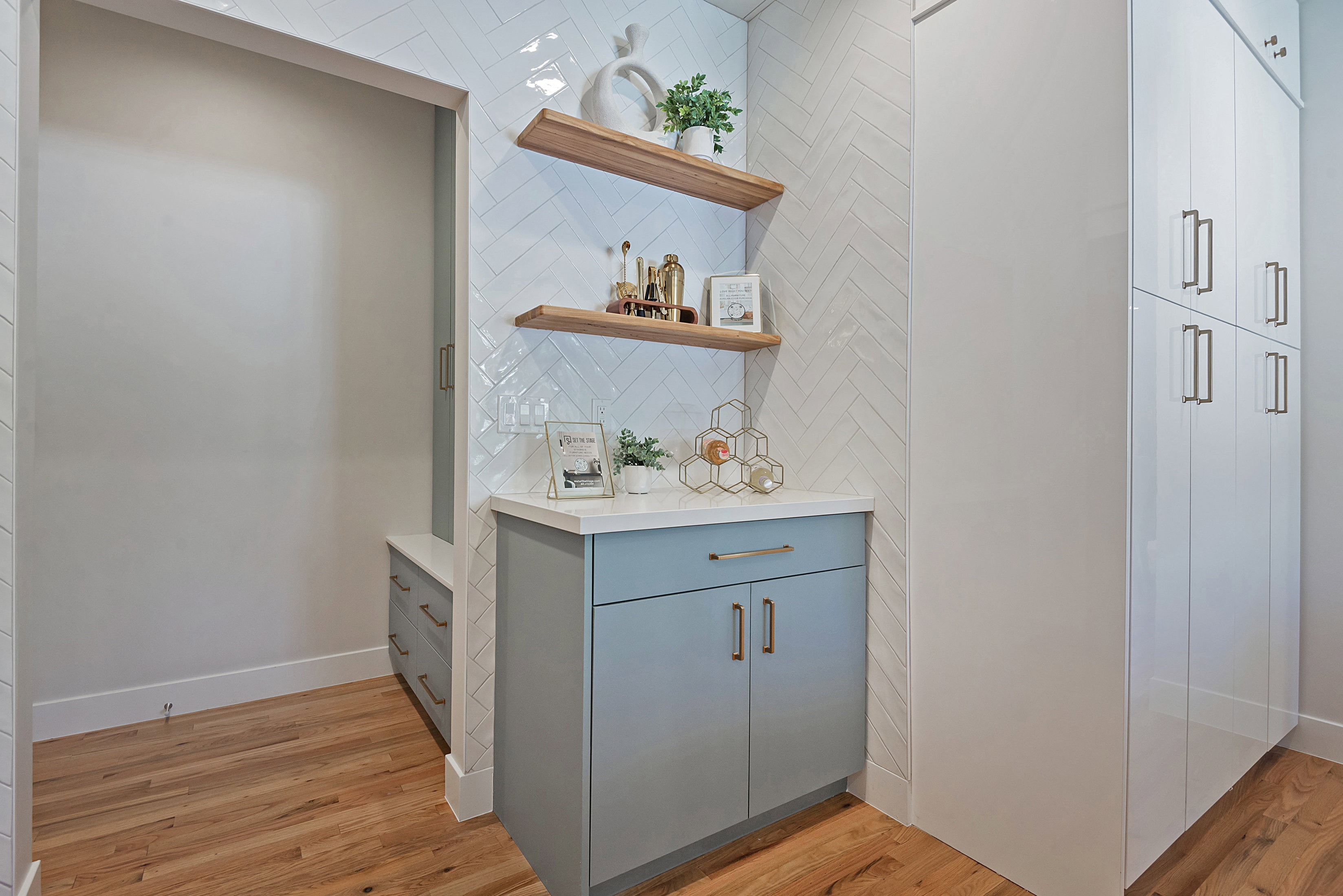 Bar featuring open shelves, light stone counters with mud room and lockers right off garage.