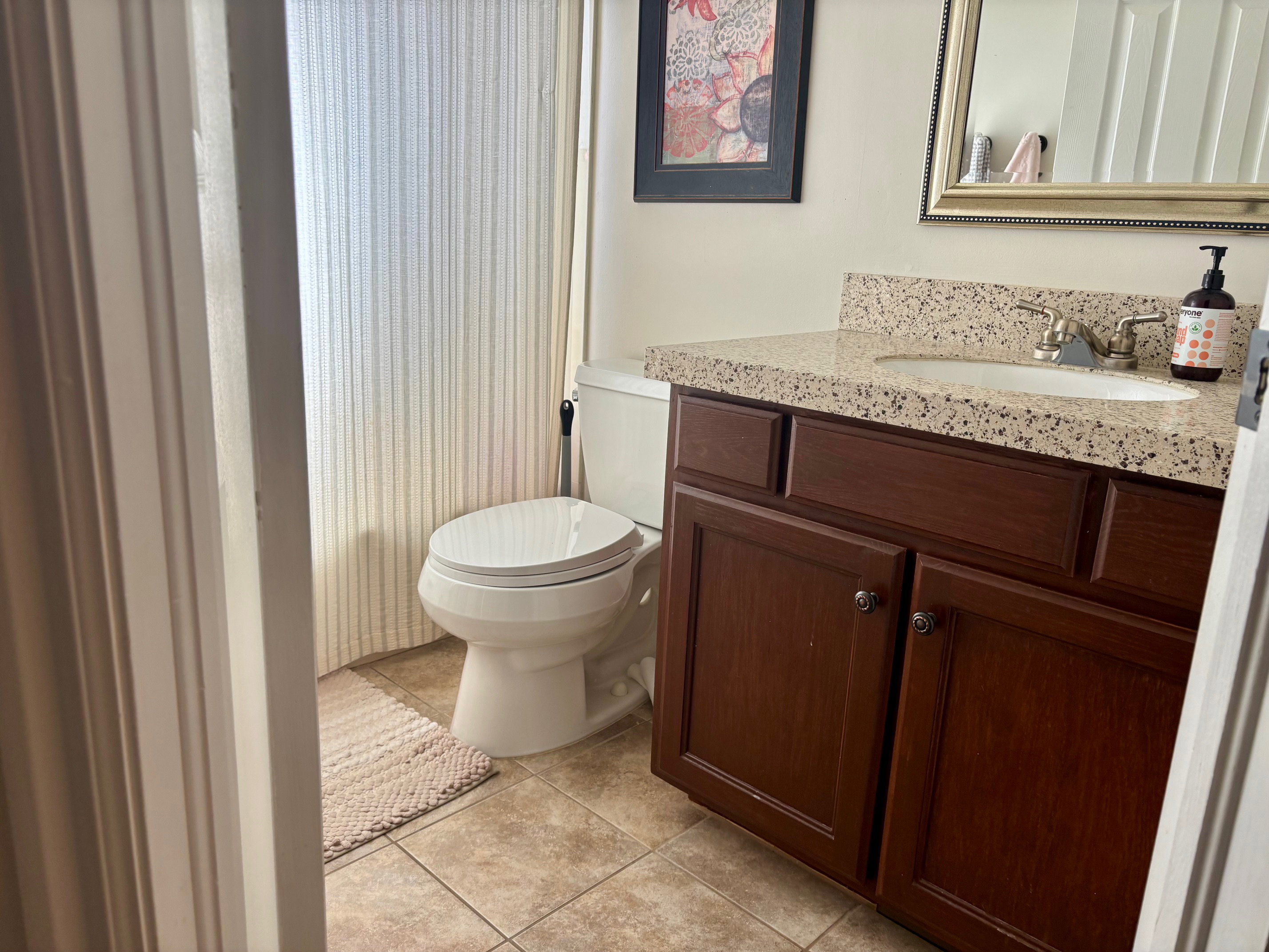Bathroom featuring a vanity with a speckled countertop, an integrated sink, dark wood-finish cabinetry, a built-in mirror, and ceramic tile flooring