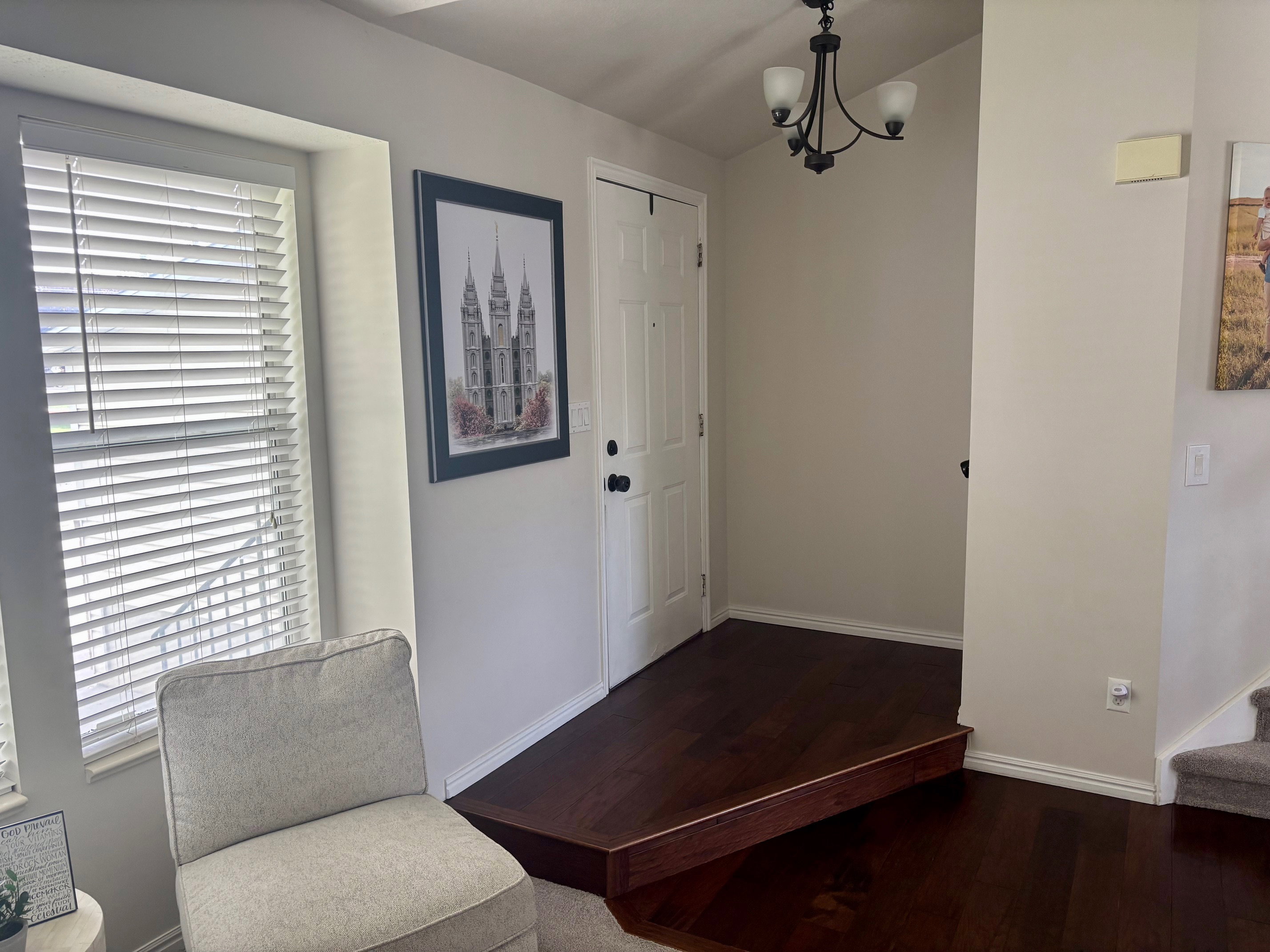 Entryway featuring dark wood-finish flooring, a white paneled door, and a traditional black chandelier