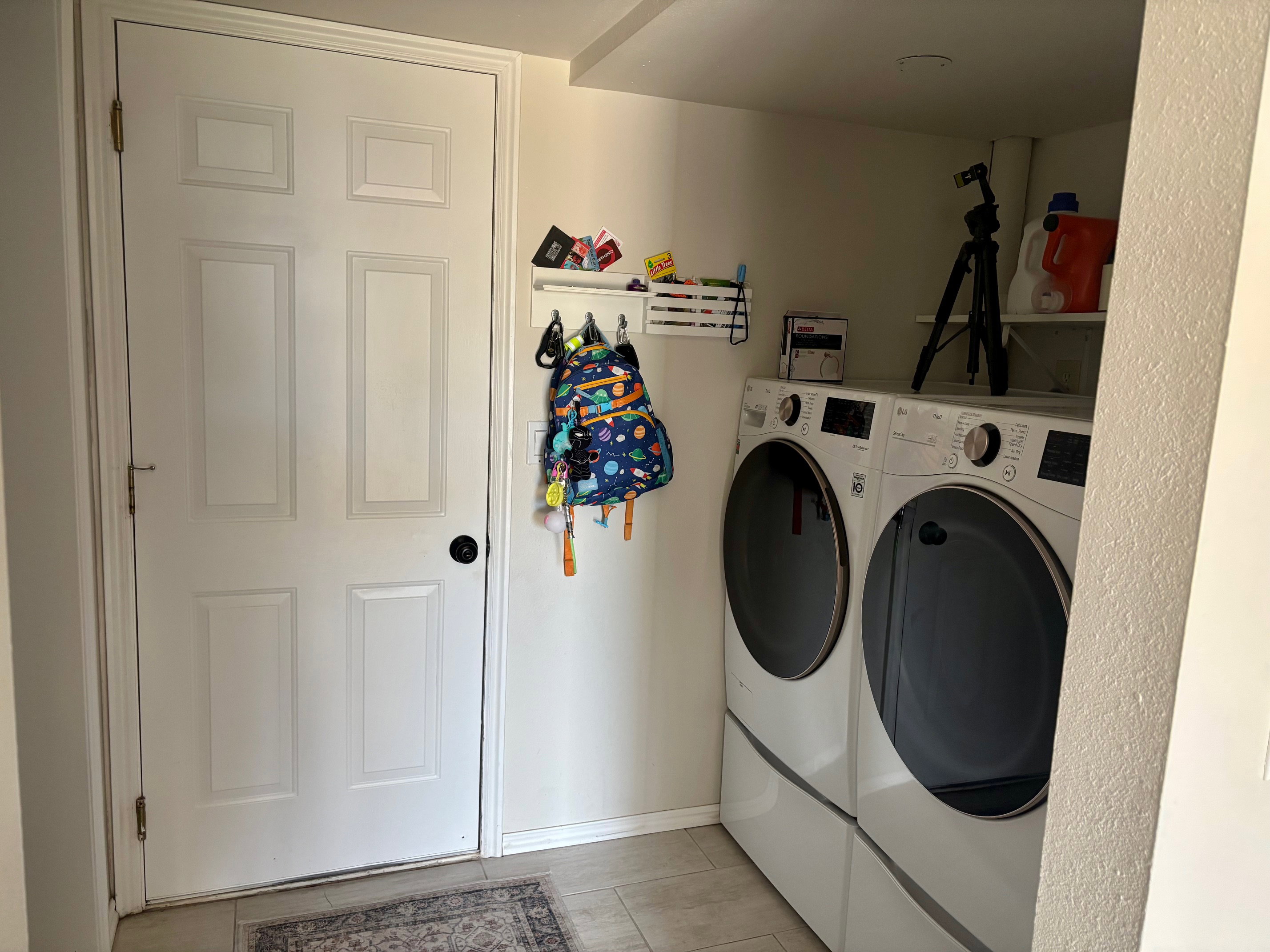 Dedicated laundry area featuring a white six-panel door, light-toned wall paint, and tiled flooring