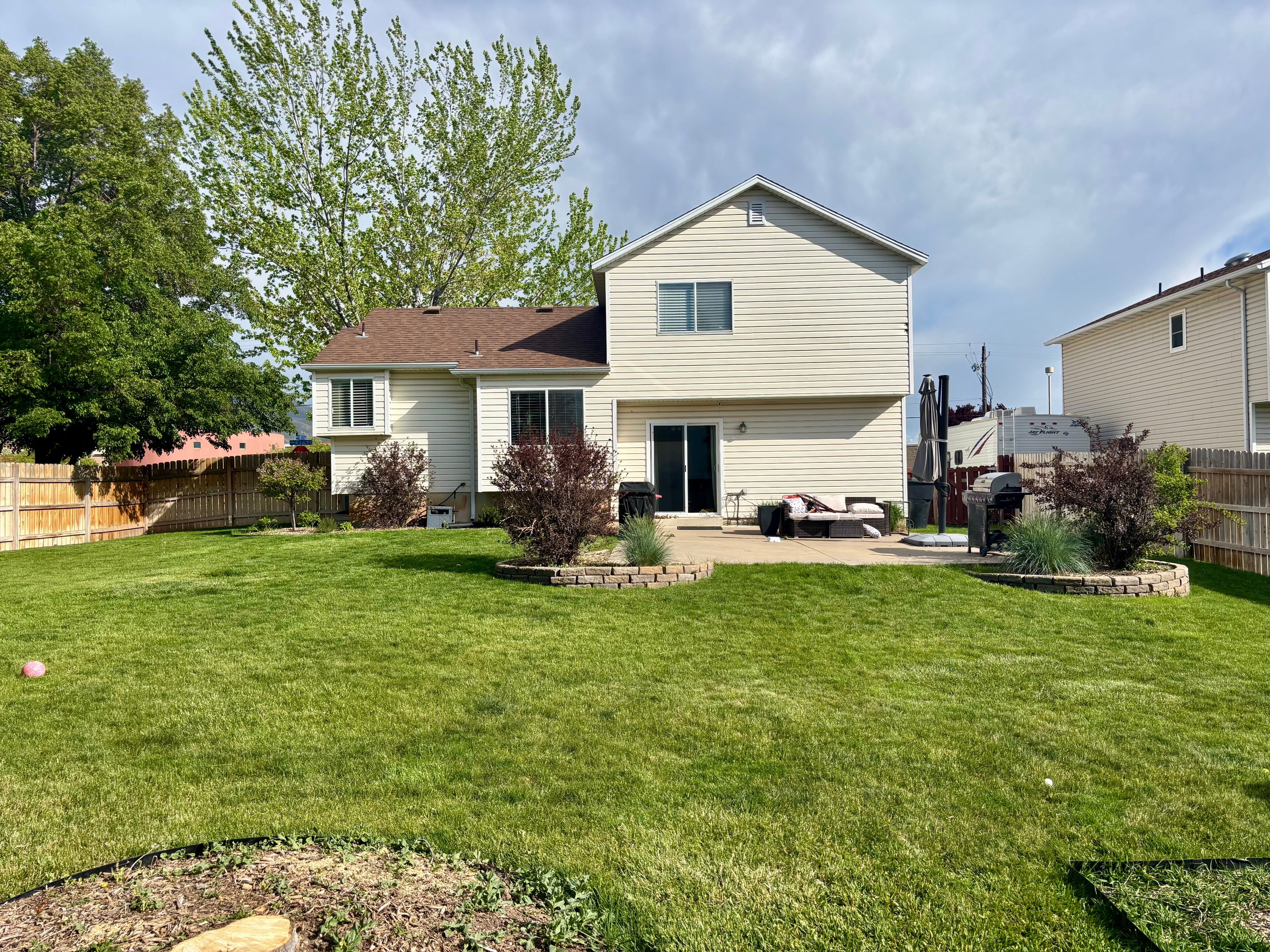 Expansive green lawn with mature trees and a private wood fence