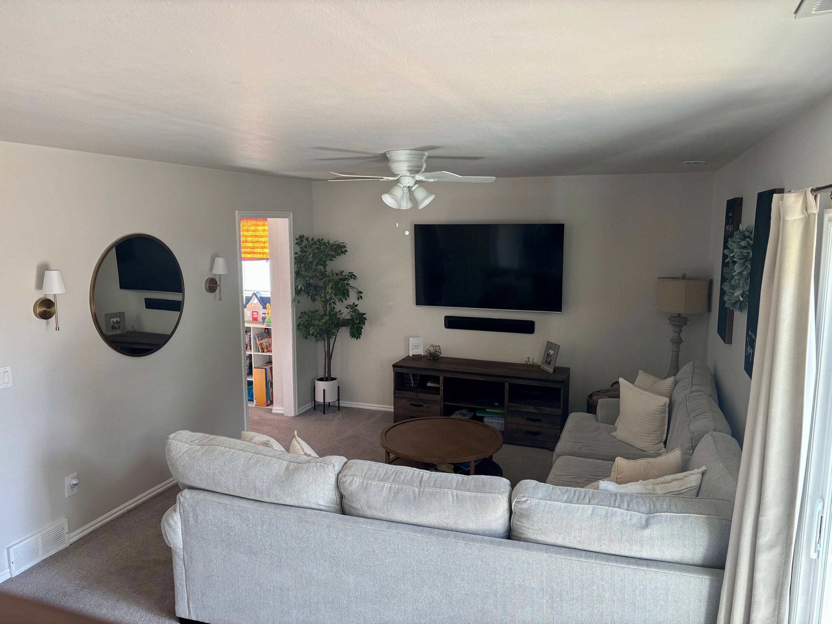 Living area featuring carpeted flooring, a ceiling fan with integrated lighting, and light-toned wall paint
