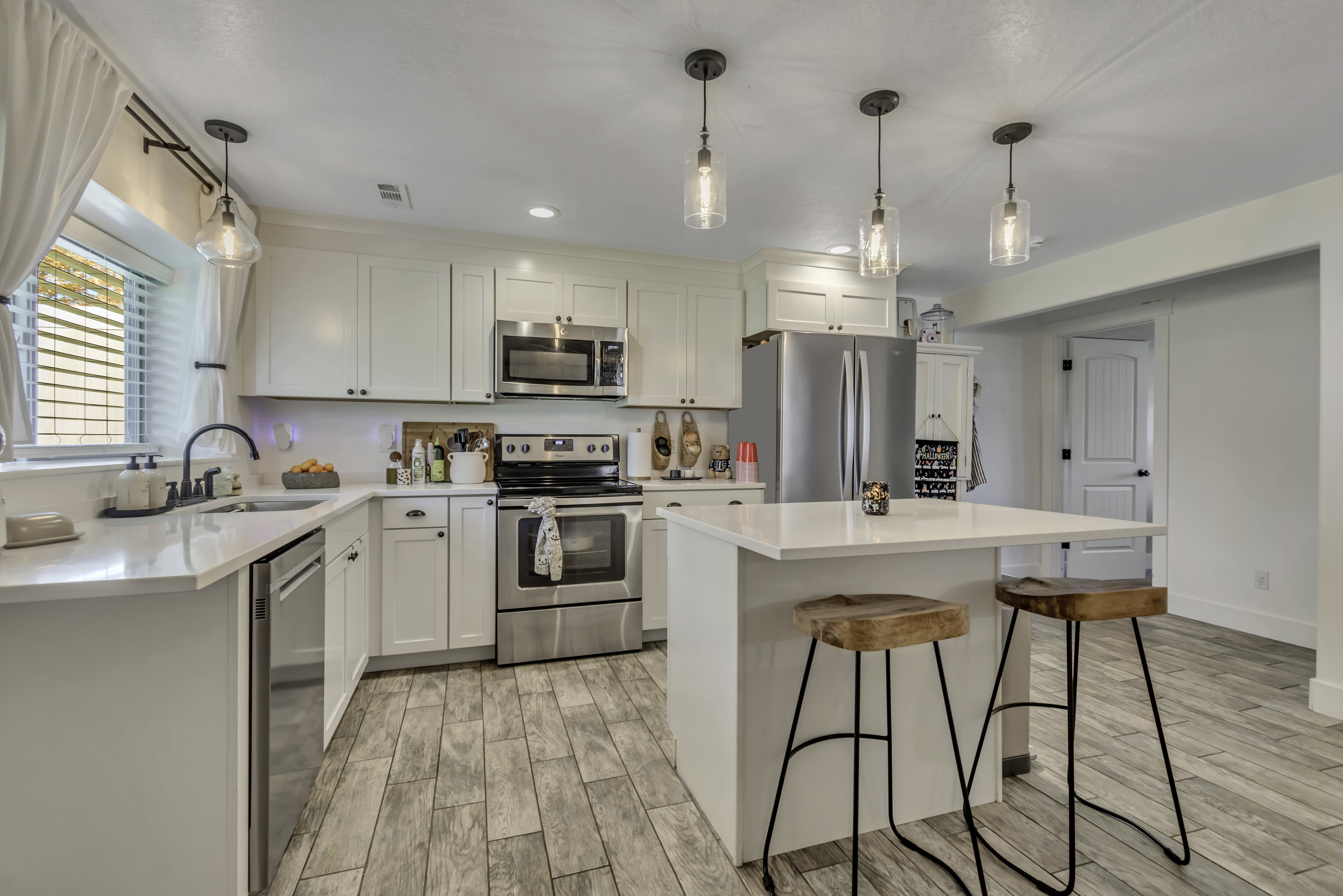 Kitchen with stainless steel appliances, wood finish floors, white cabinets, and a kitchen bar