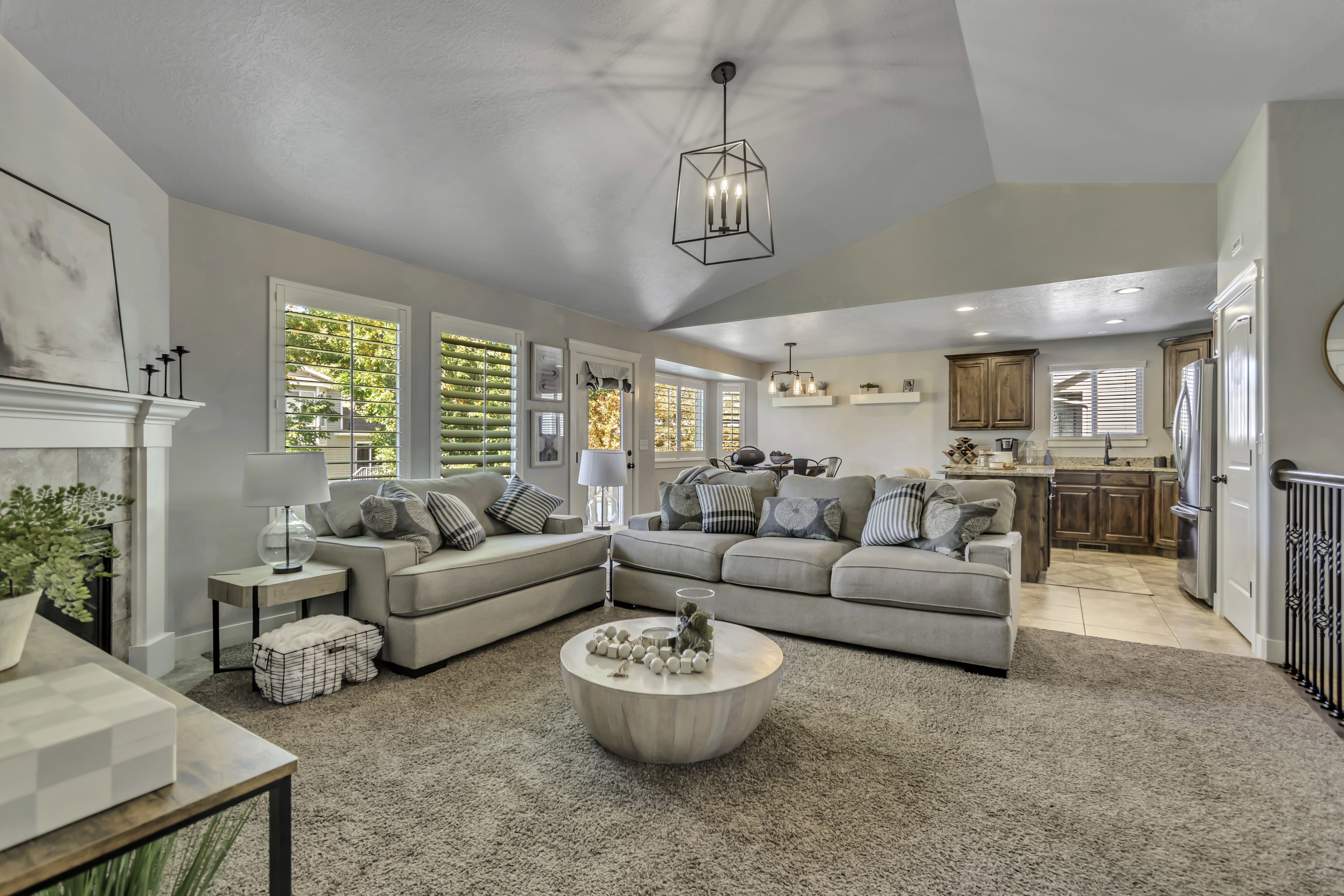 Living room with light colored carpet, lofted ceiling, hanging lights, and a fireplace