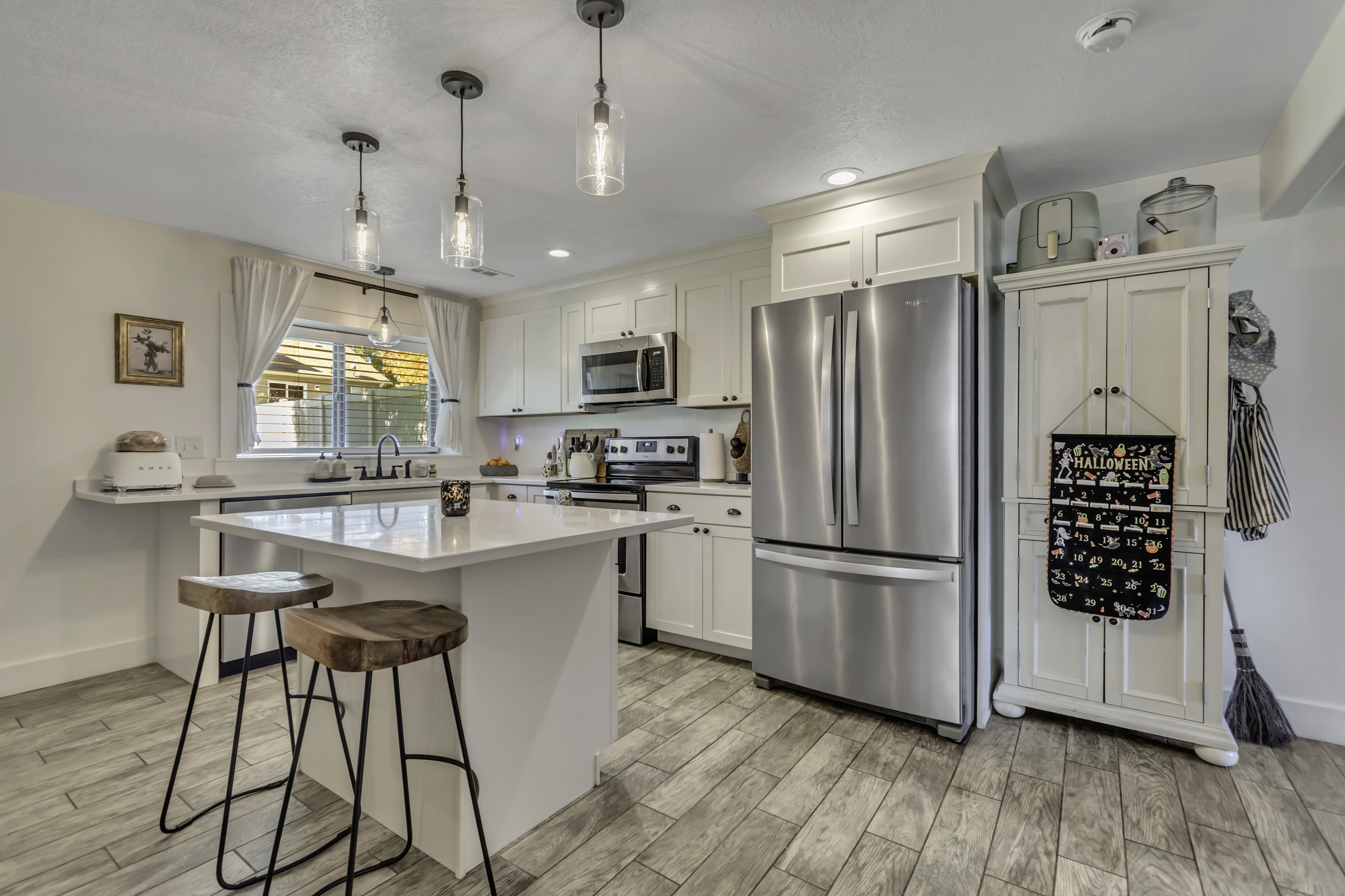 Kitchen with stainless steel appliances, a kitchen breakfast bar, wood tiled floors, and white cabinets