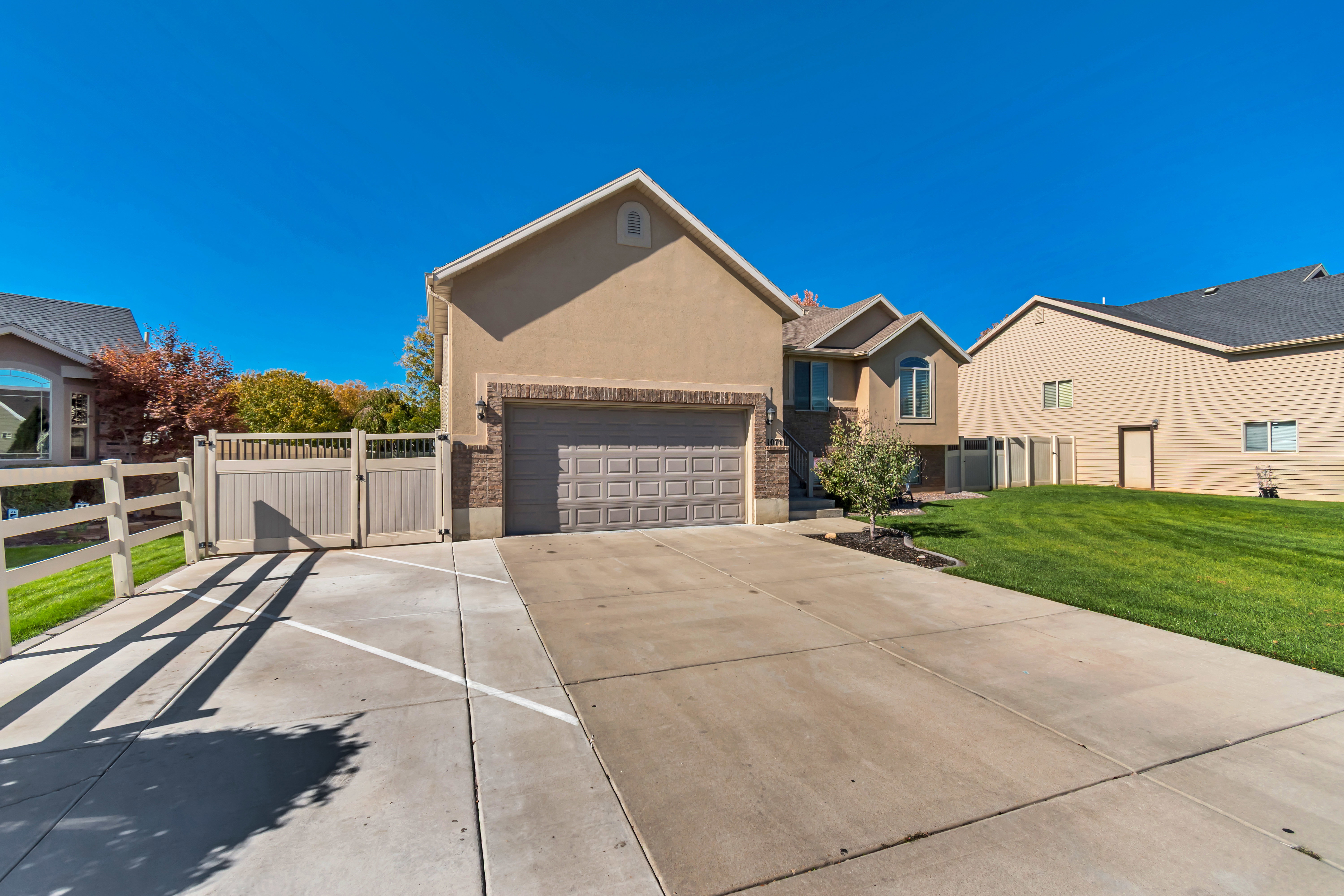 Ranch-style home with a gate, stucco siding, and concrete driveway