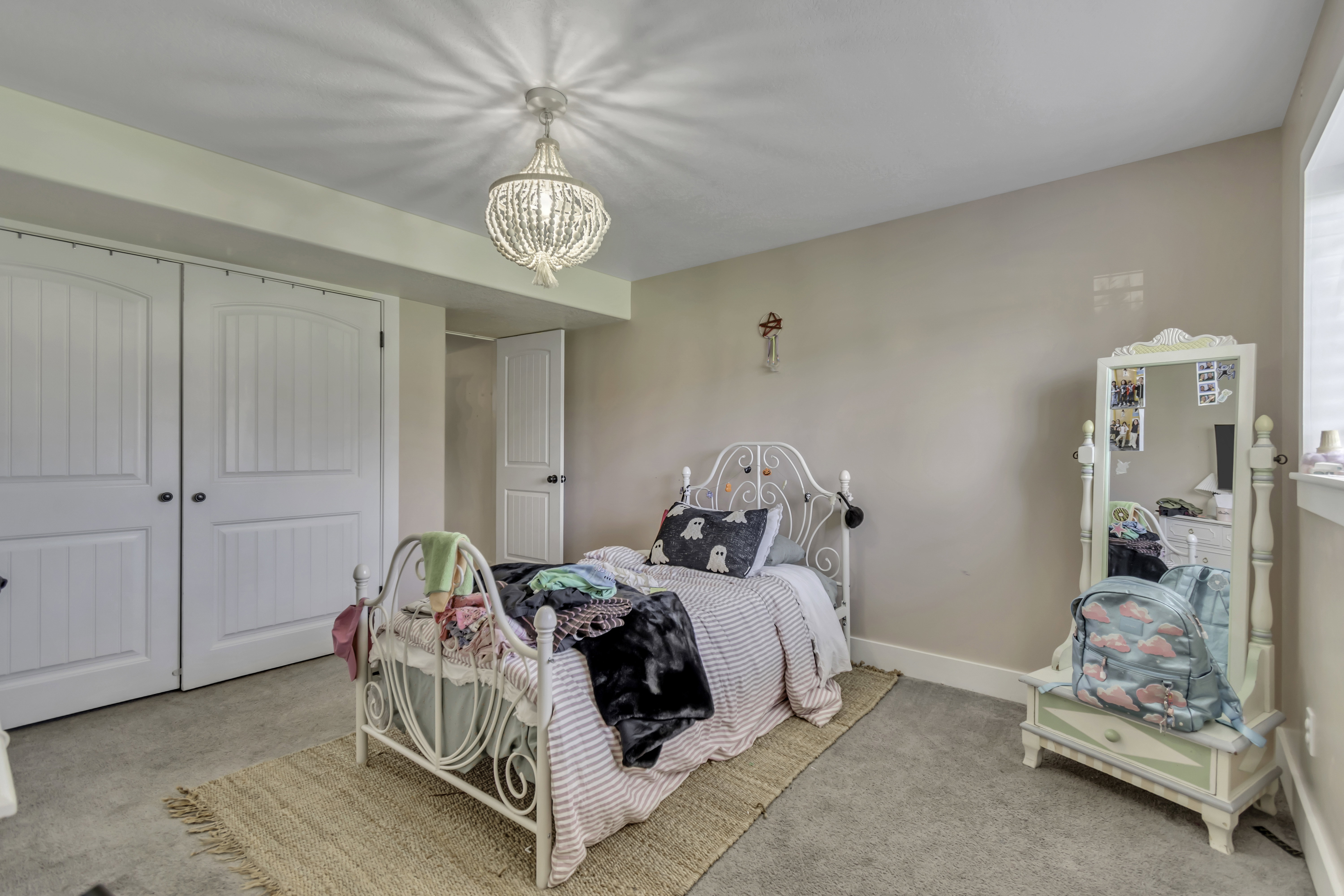 Bedroom with light colored carpet, a closet, and hanging lights