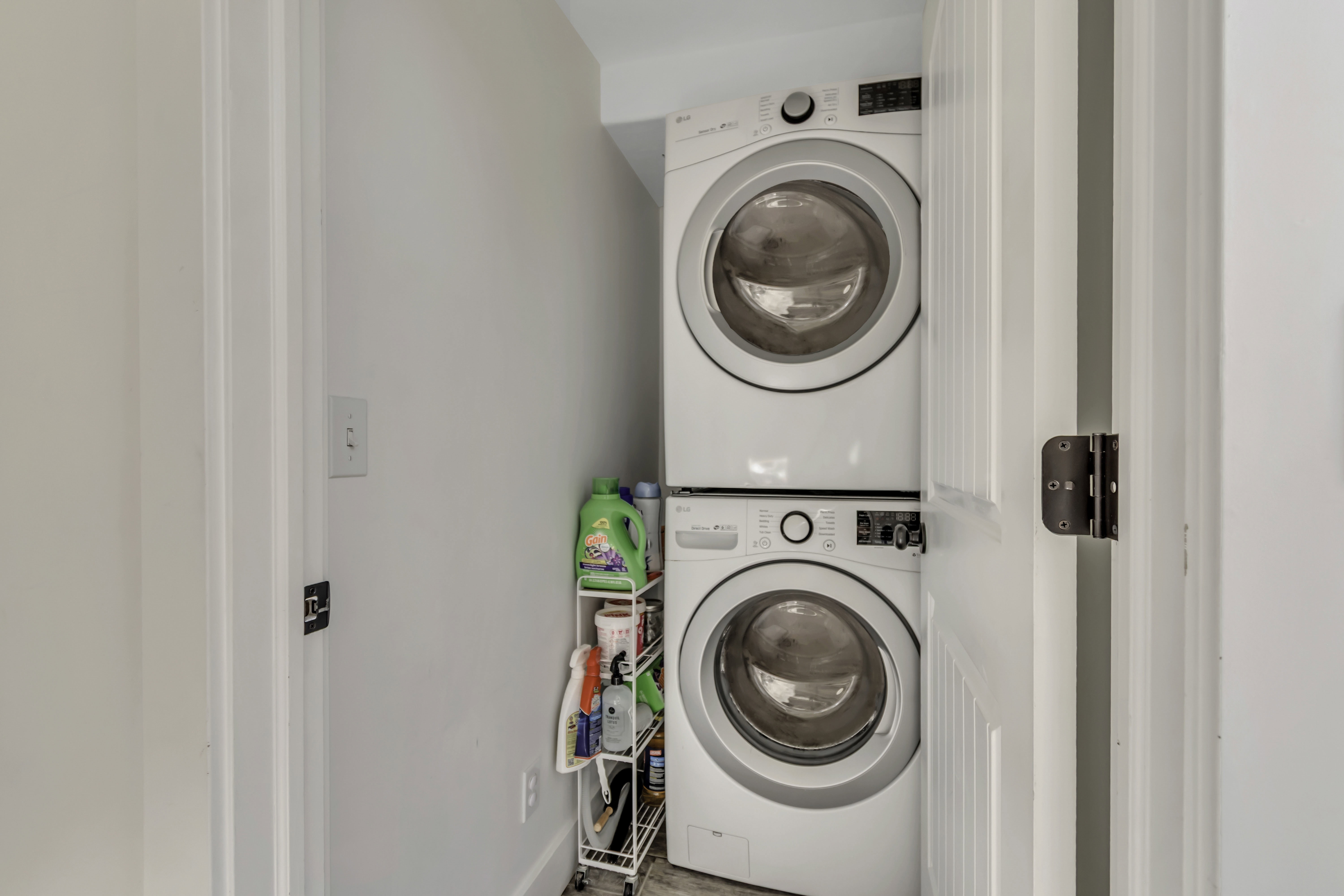 Laundry area with stacked washer and clothes dryer and baseboards