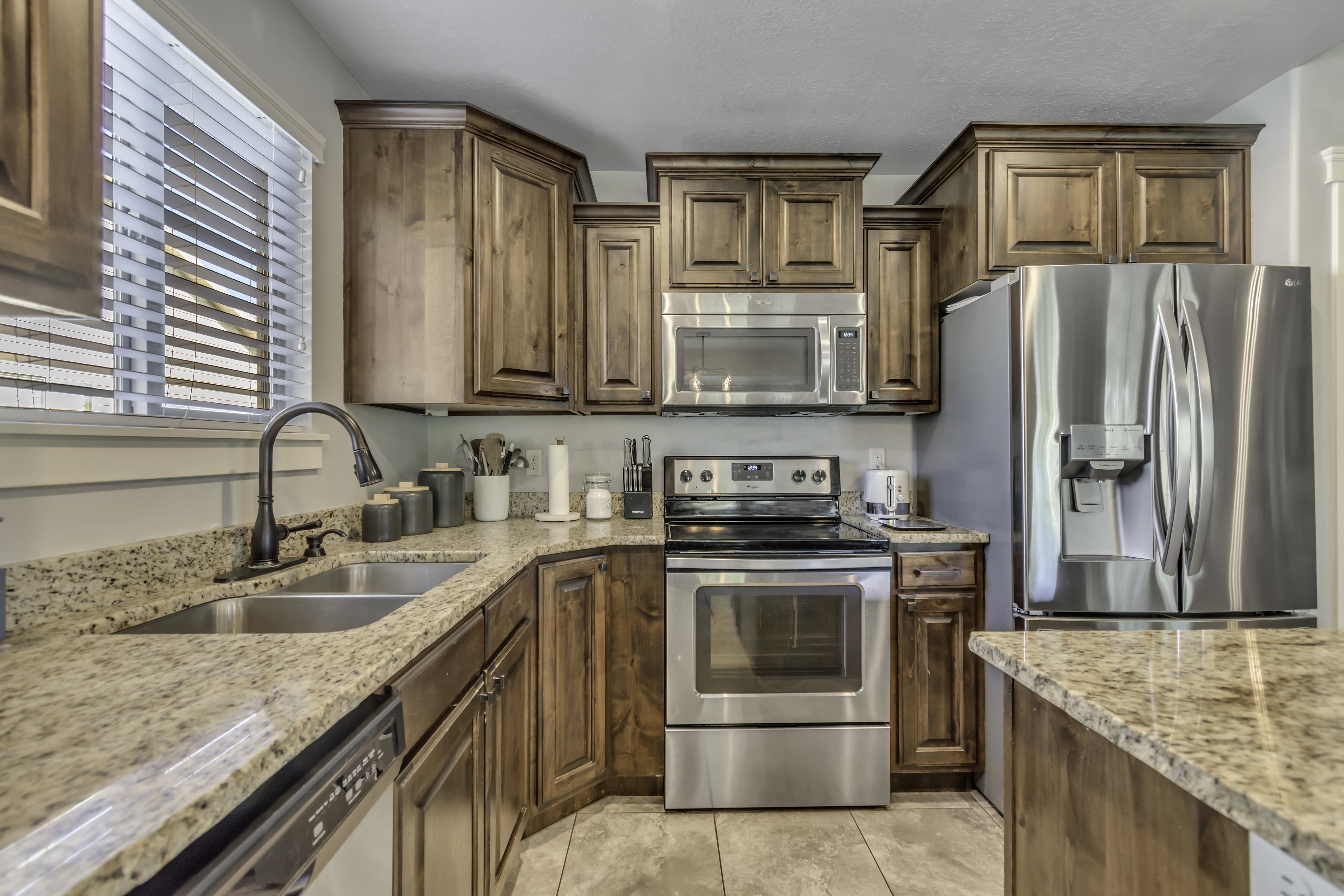 Kitchen with stainless steel appliances, light stone counters, and wood finish cabinets