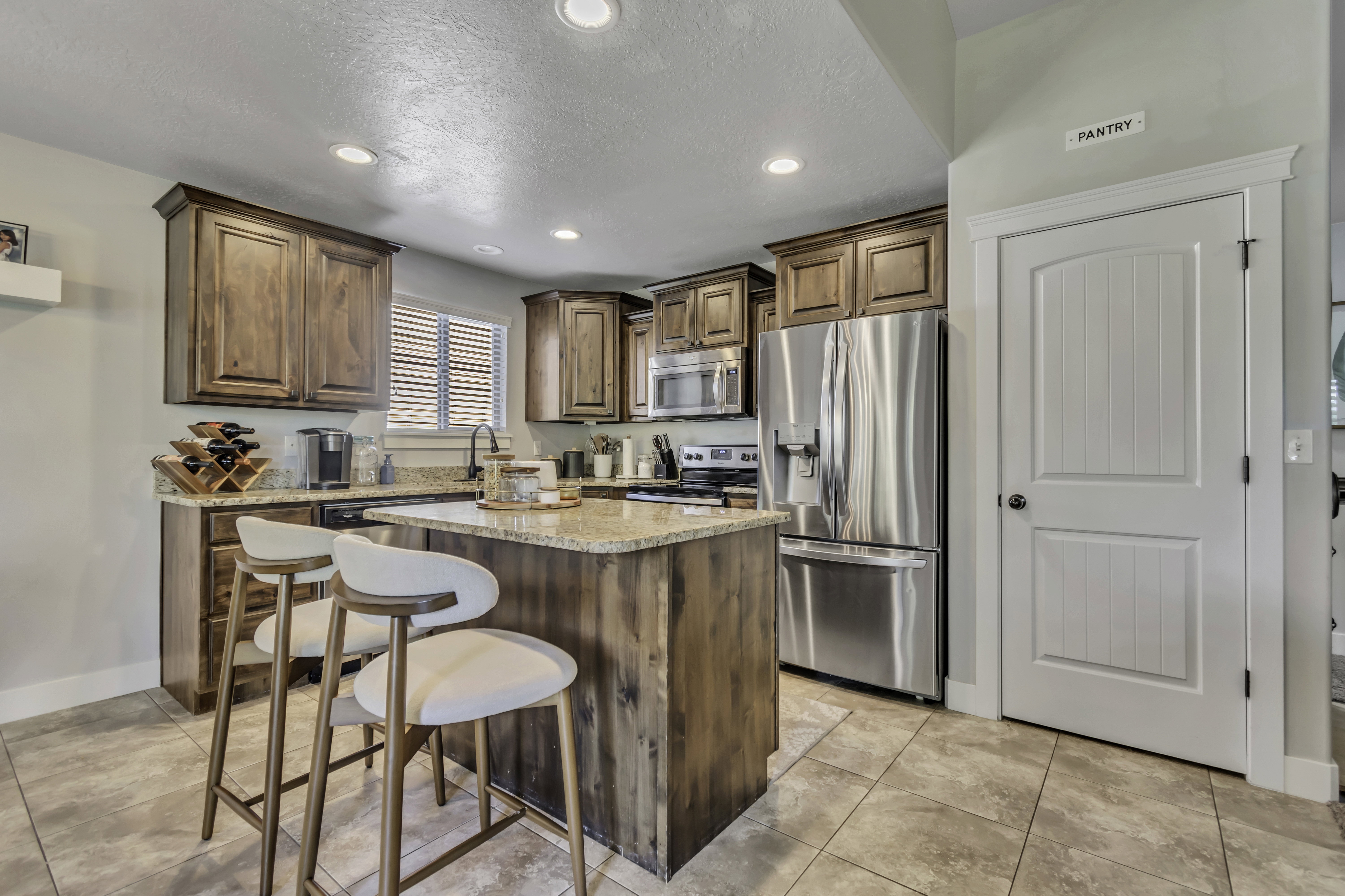 Kitchen with stainless steel appliances, light stone counters, a center island, wood finish cabinetry, and a breakfast bar