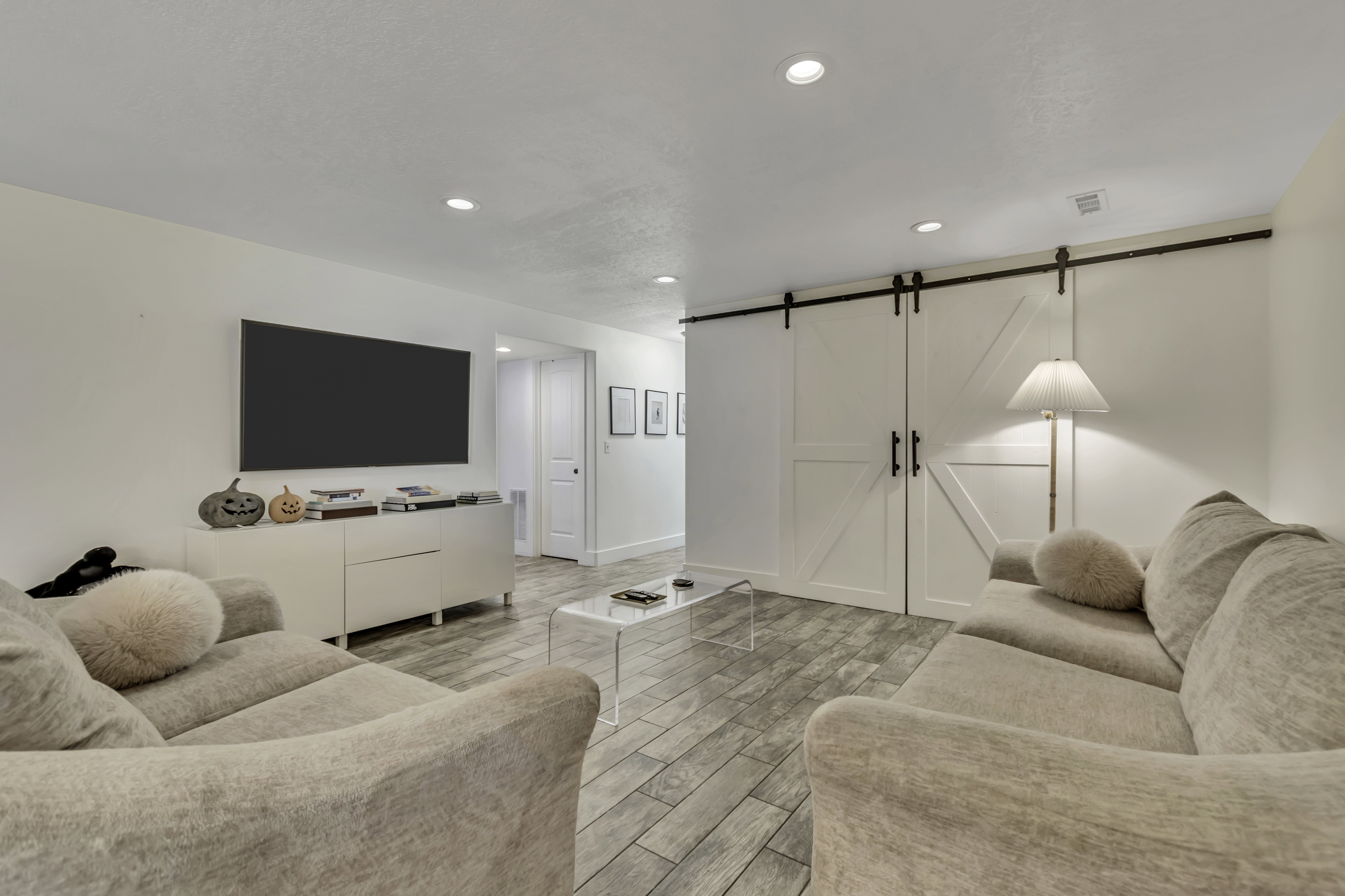 Living room with a barn door, wood tiled floors, and recessed lighting