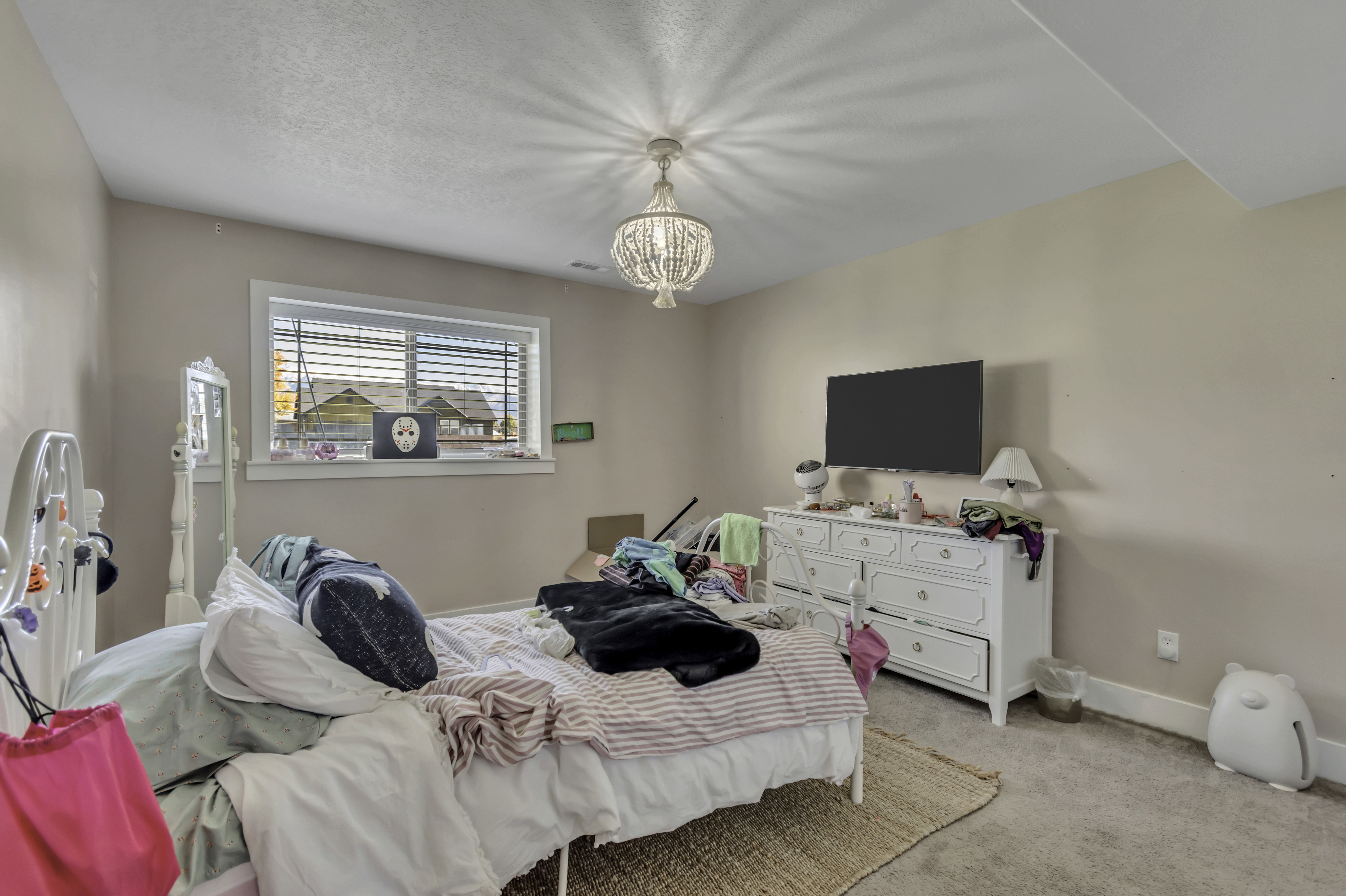 Bedroom with light colored carpet and a chandelier