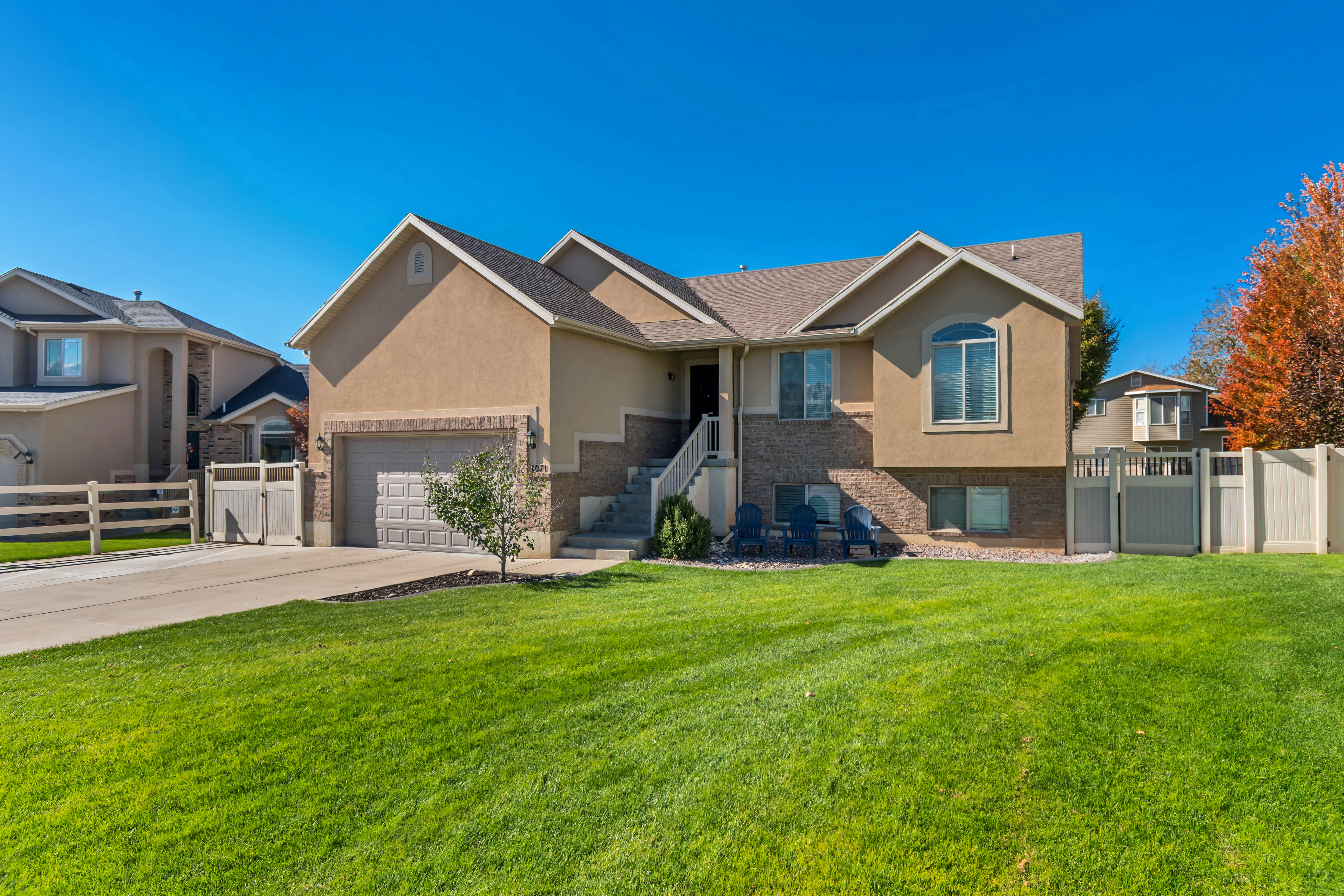 Ranch-style home featuring a gate, stucco siding, concrete driveway, a garage, and brick siding