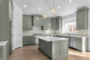 Contemporary kitchen featuring light green cabinetry, white countertops, wood-finish flooring, and stainless steel appliances