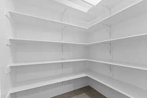 Expansive pantry featuring white shelving, multiple storage tiers, and a skylight