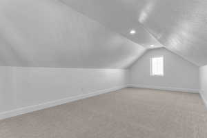 Carpeted room with vaulted ceilings, recessed lighting, and a single pane window