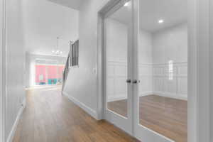 Entryway featuring wood-finish flooring, a contemporary chandelier, and a white spindle staircase